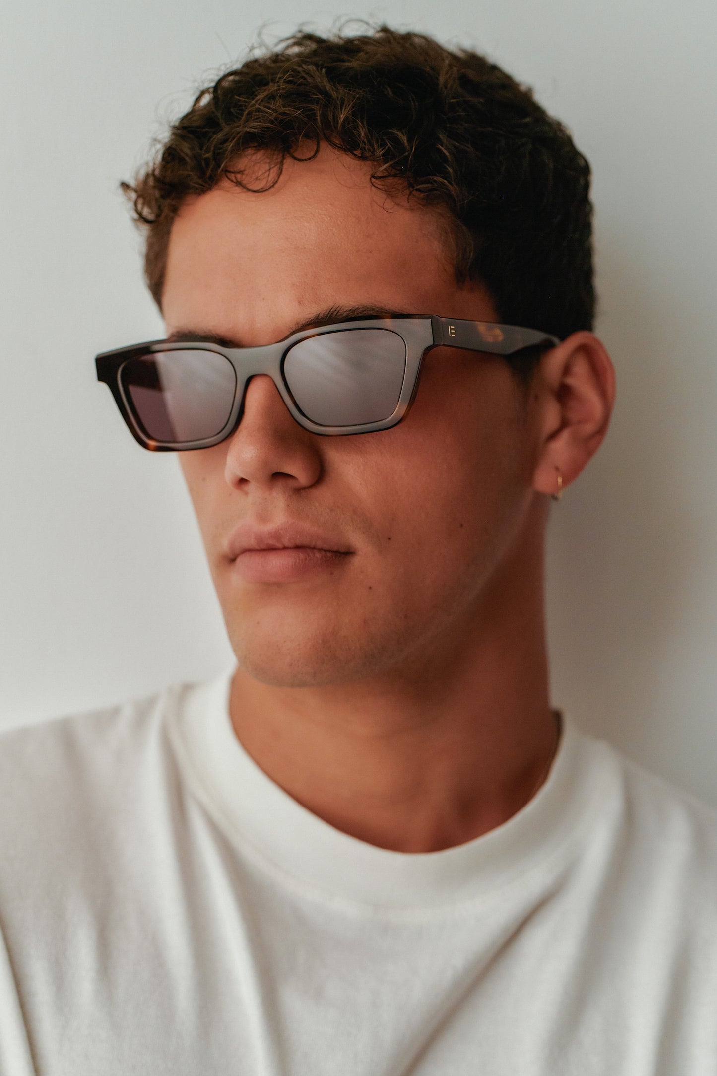 Male model wearing Isle of Eden Brooklyn tortoise sunglasses, front-facing portrait showing rectangular frame fit