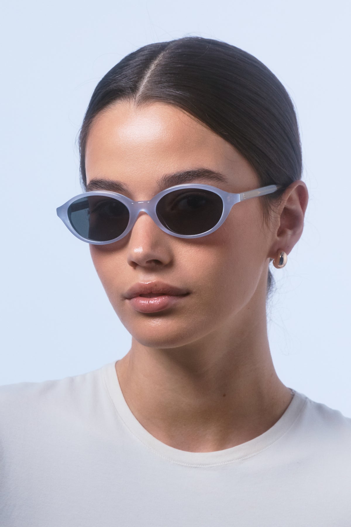 Female model wearing Isle of Eden Mirabel baby blue sunglasses, close front-facing portrait