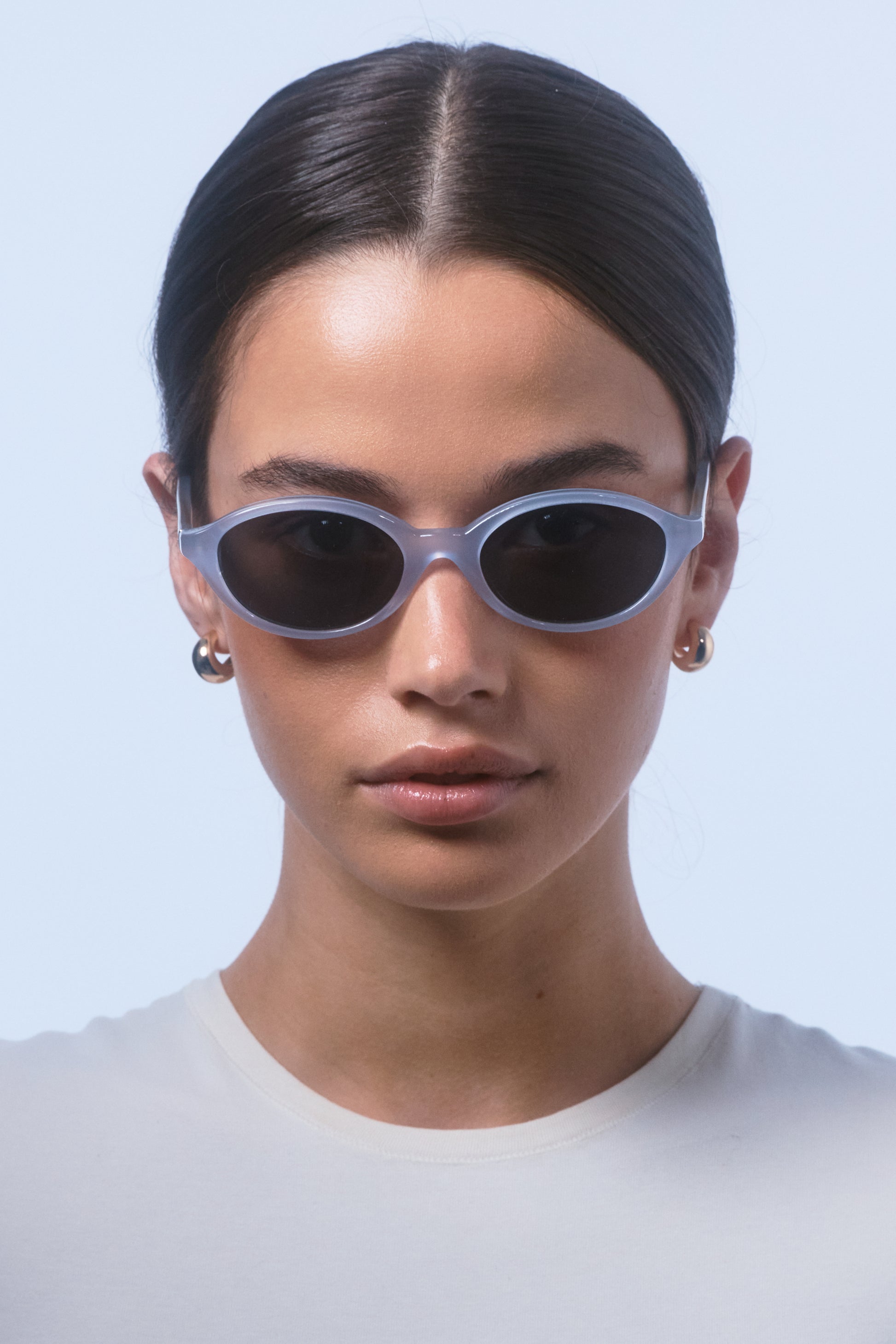 Female model wearing Isle of Eden Mirabel baby blue sunglasses, front-facing portrait looking directly at the camera