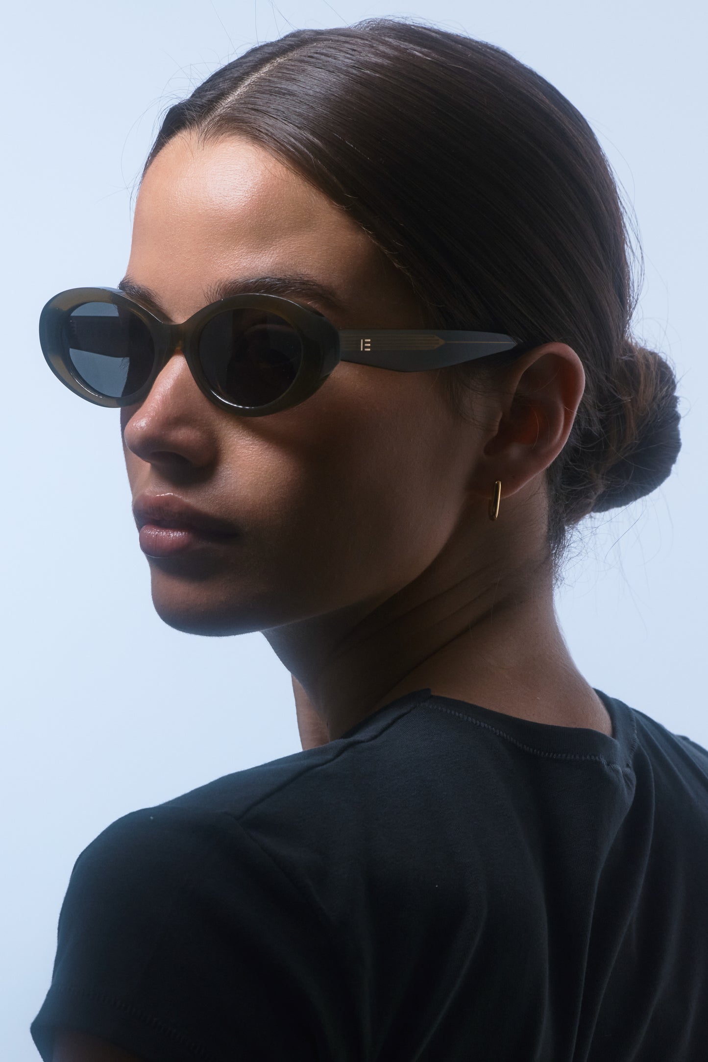Female model wearing Isle of Eden Frankie frosted green sunglasses, angled portrait looking away
