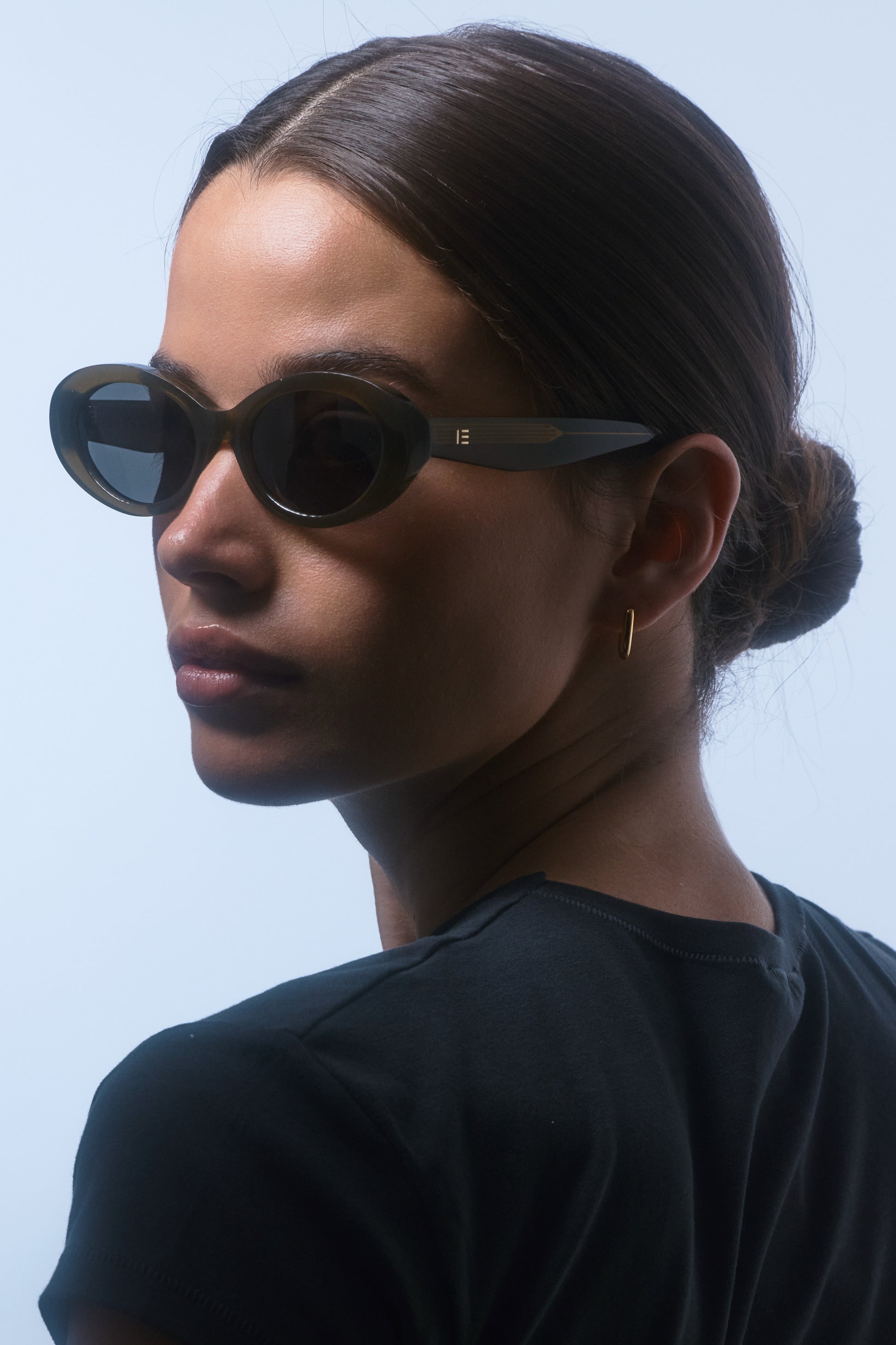 Female model wearing Isle of Eden Frankie frosted green sunglasses, angled portrait looking away