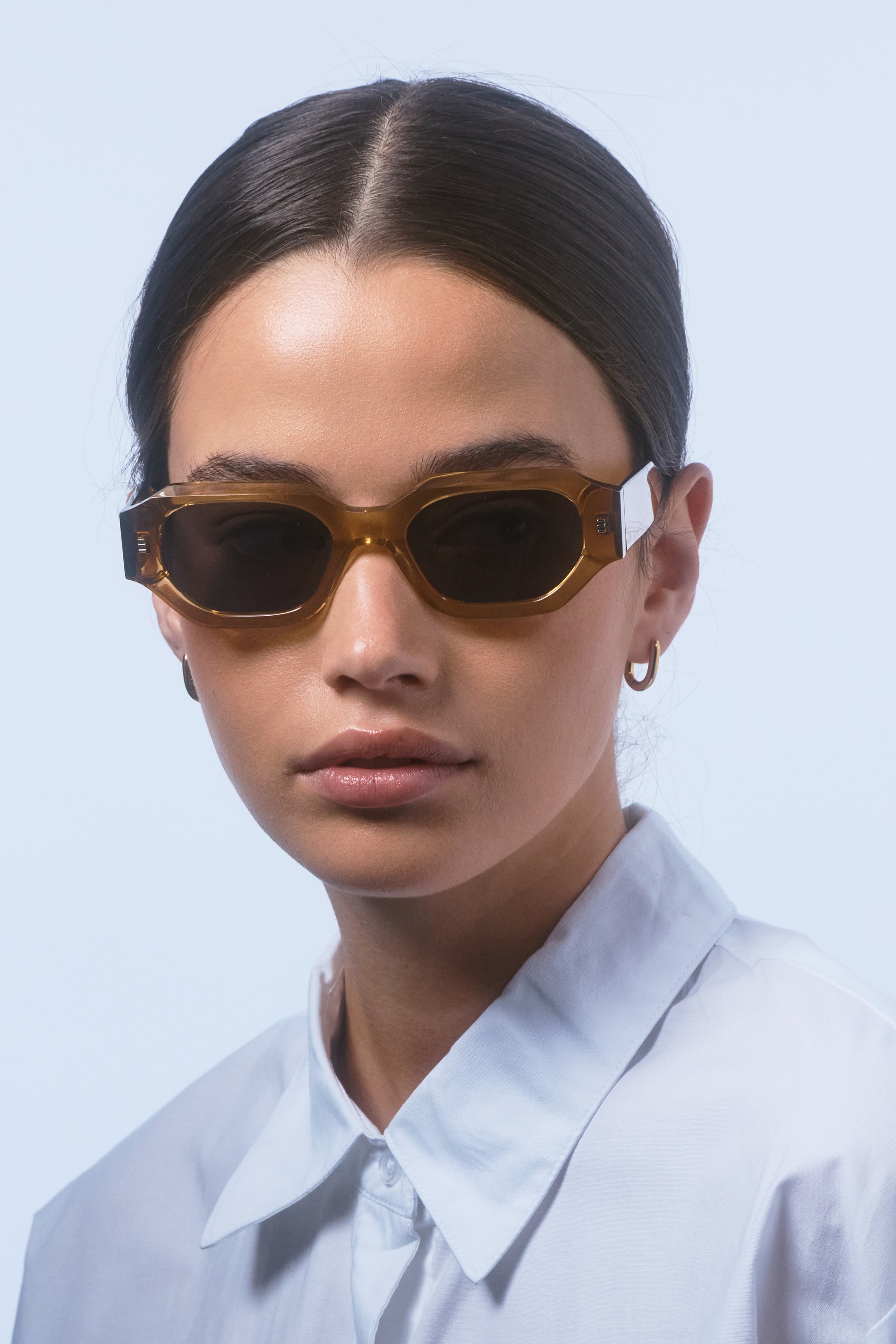 Model wearing Isle of Eden Blake cognac sunglasses, front-facing portrait showing hexagonal frame fit