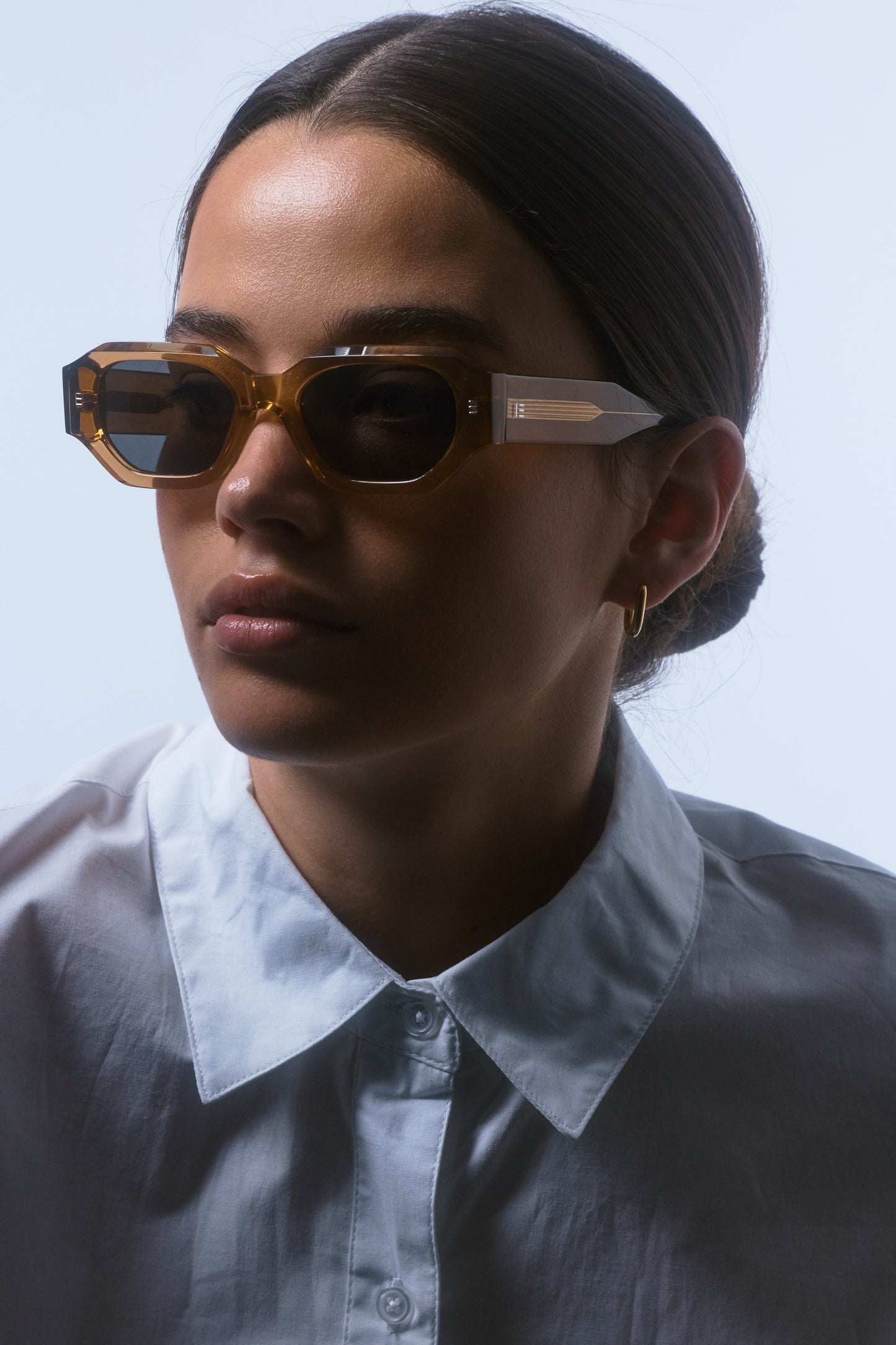 Model wearing Isle of Eden Blake cognac sunglasses, angled side profile showing hexagonal frame and temple arm
