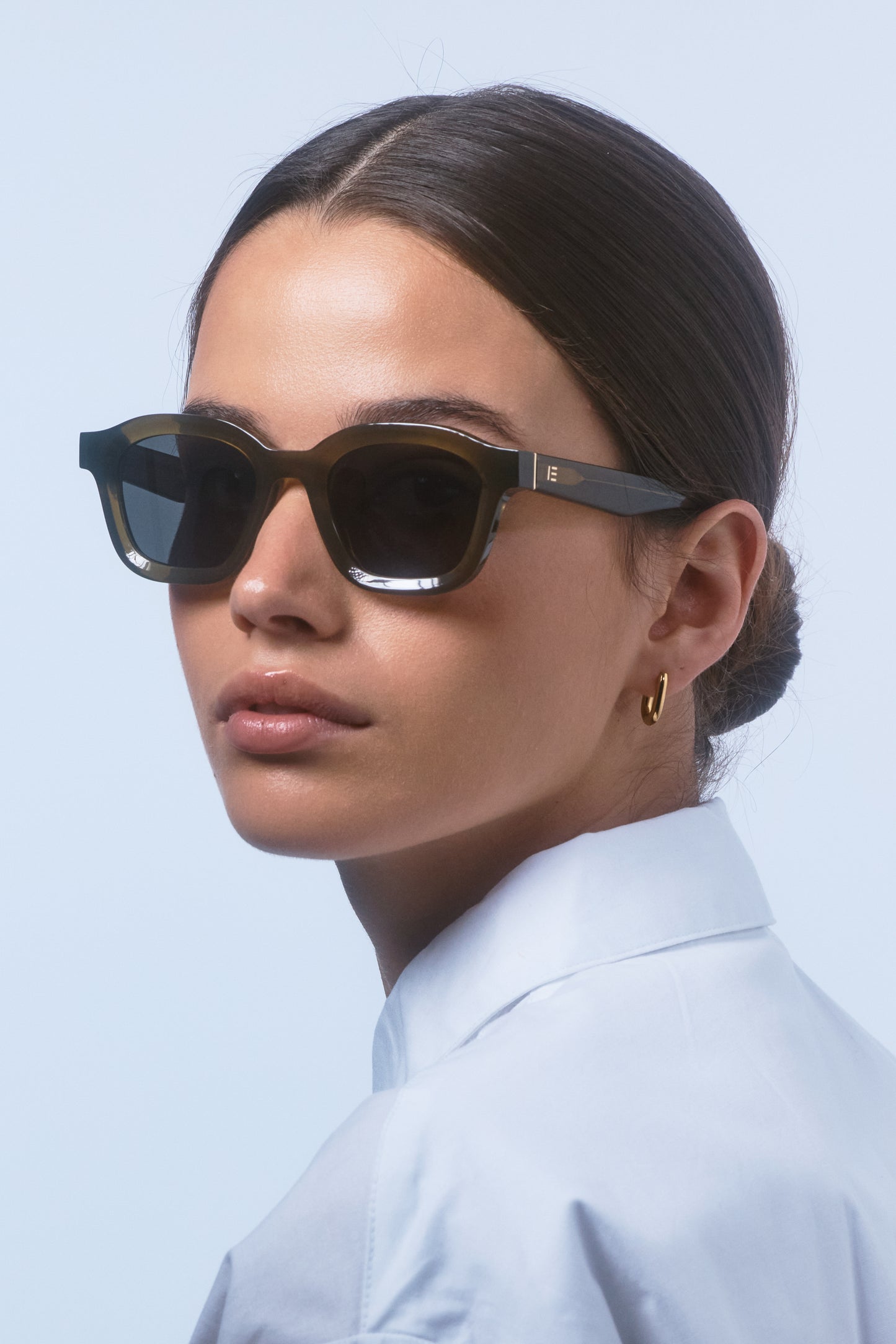 Female model wearing Isle of Eden Harley frosted green sunglasses, portrait looking away