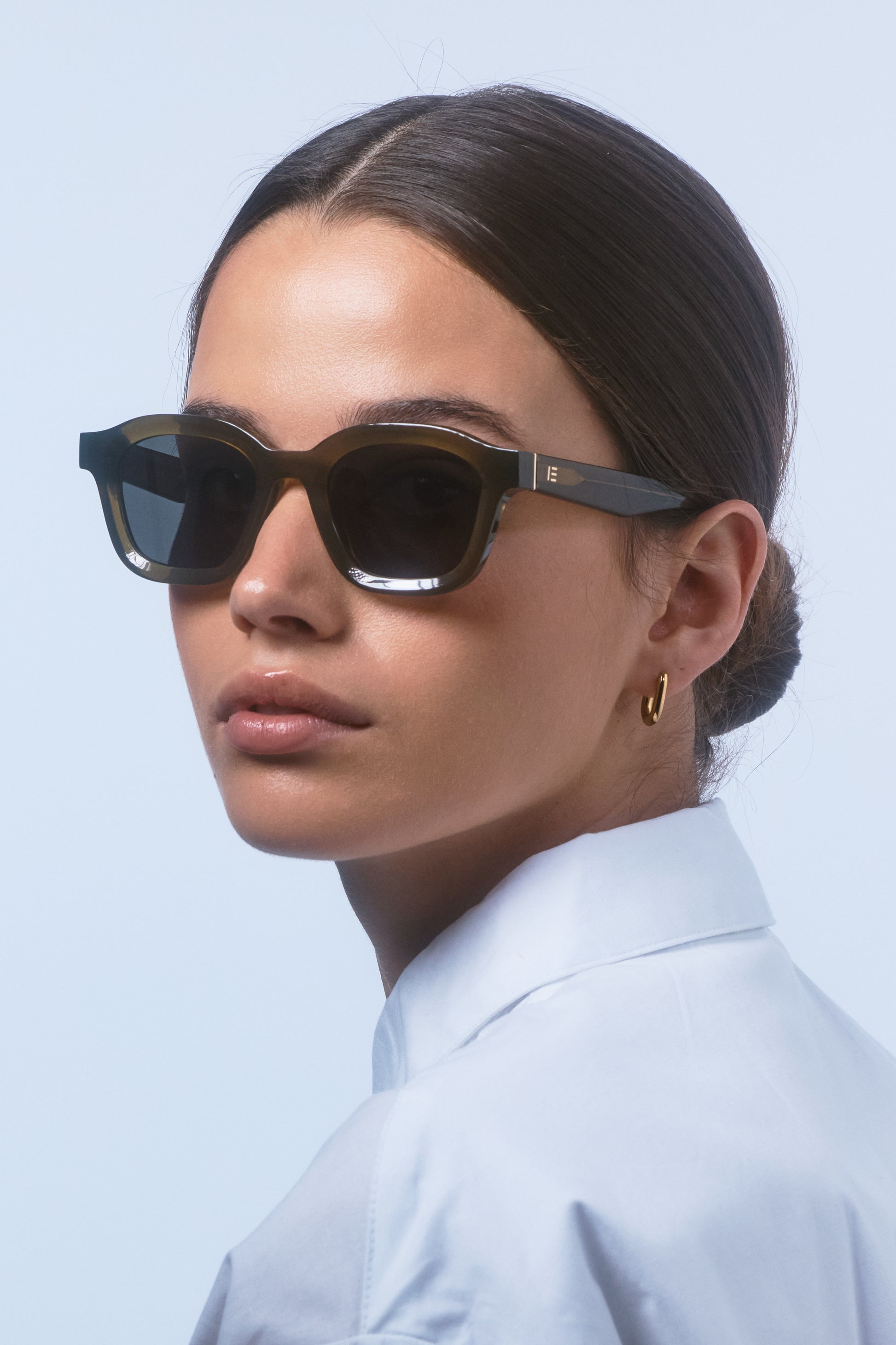 Female model wearing Isle of Eden Harley frosted green sunglasses, portrait looking away