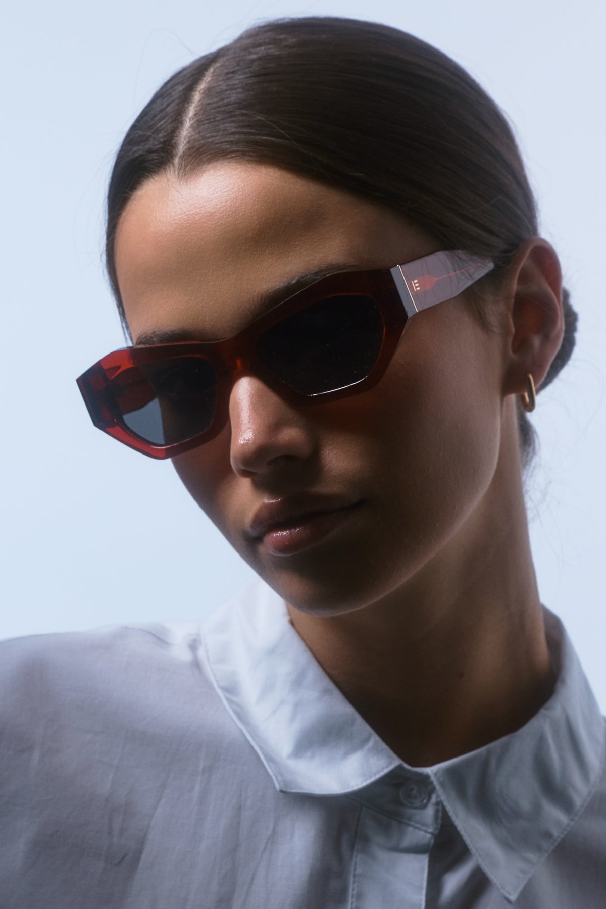 Female model wearing Isle of Eden Emily red sunglasses, angled portrait looking down