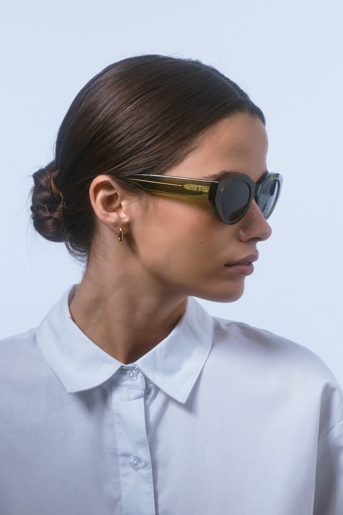 Female model wearing Isle of Eden Felina frosted green sunglasses, side profile portrait looking away