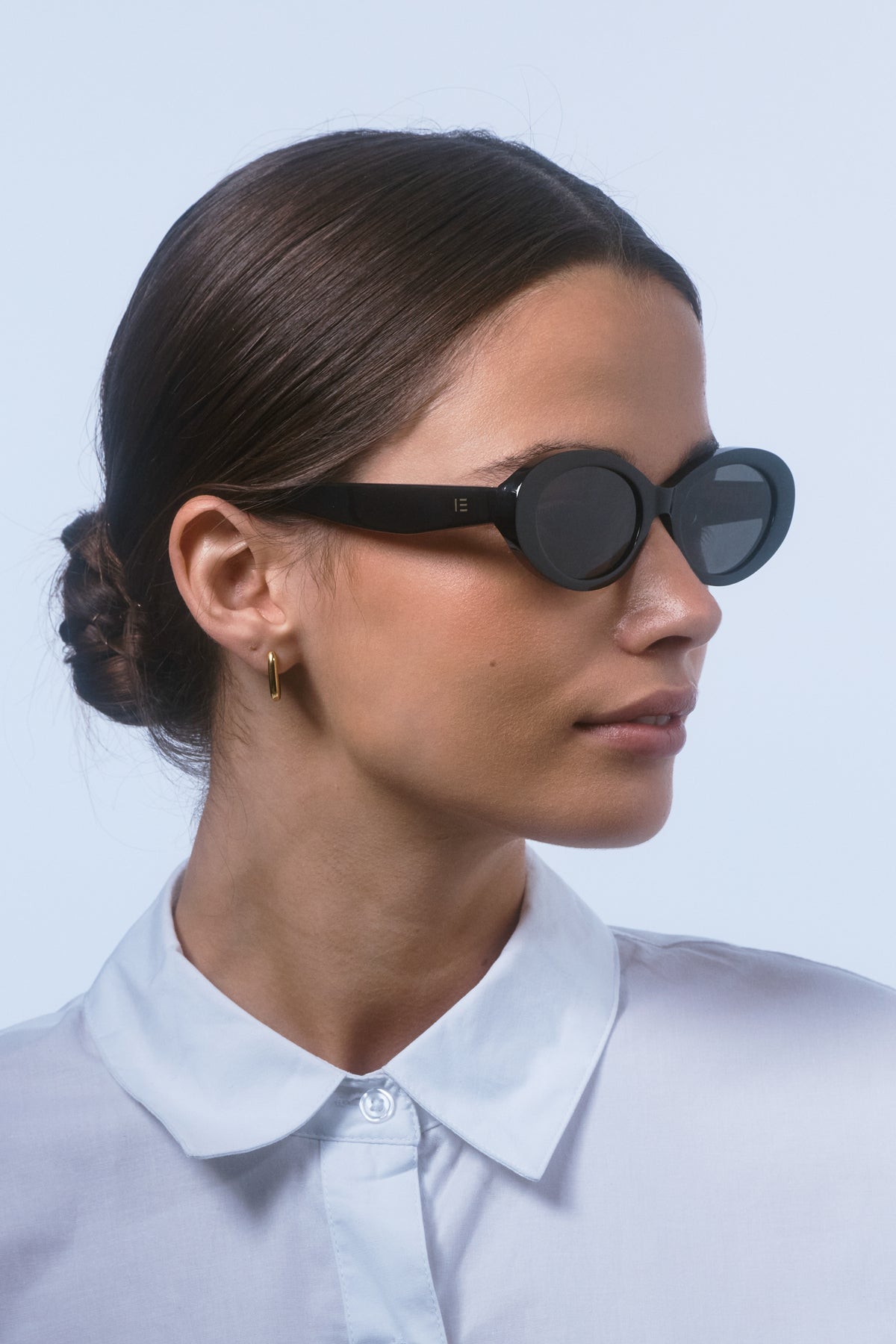 Female model wearing Isle of Eden Frankie black sunglasses, angled portrait looking away