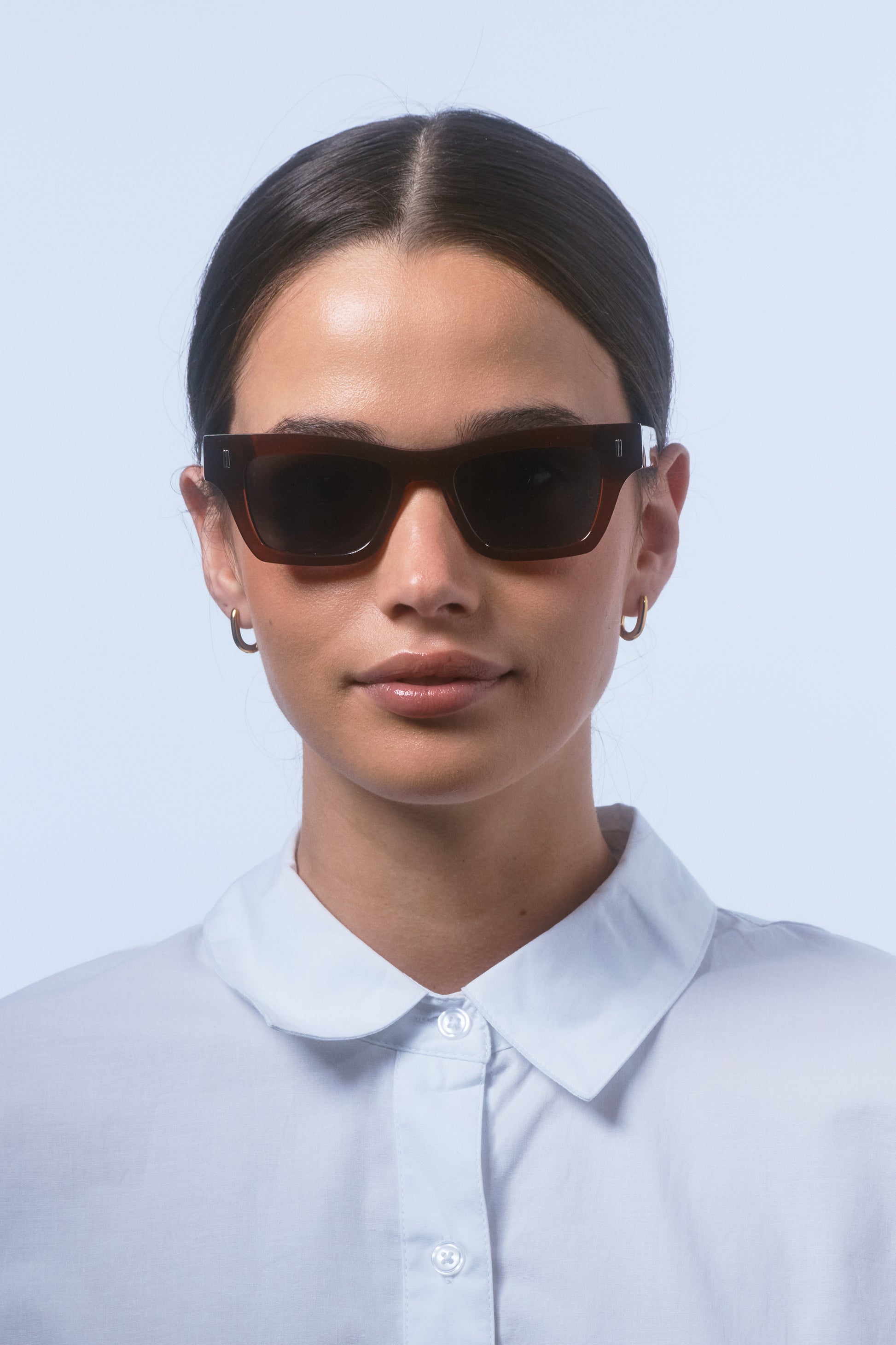 Female model wearing Isle of Eden Olli brown sunglasses, front-facing portrait looking directly at the camera