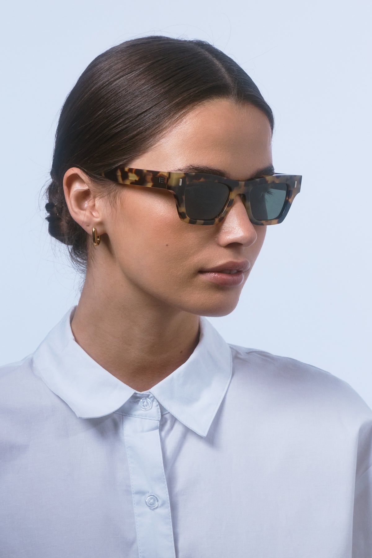 Female model wearing Isle of Eden Olli tortoise sunglasses, angled portrait looking away