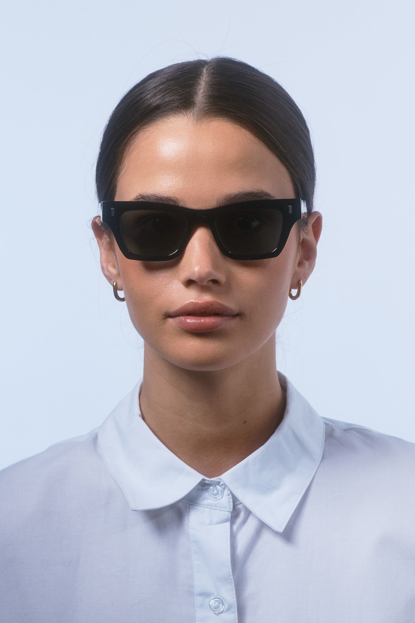 Female model wearing Isle of Eden Olli black sunglasses, front-facing portrait looking directly at the camera