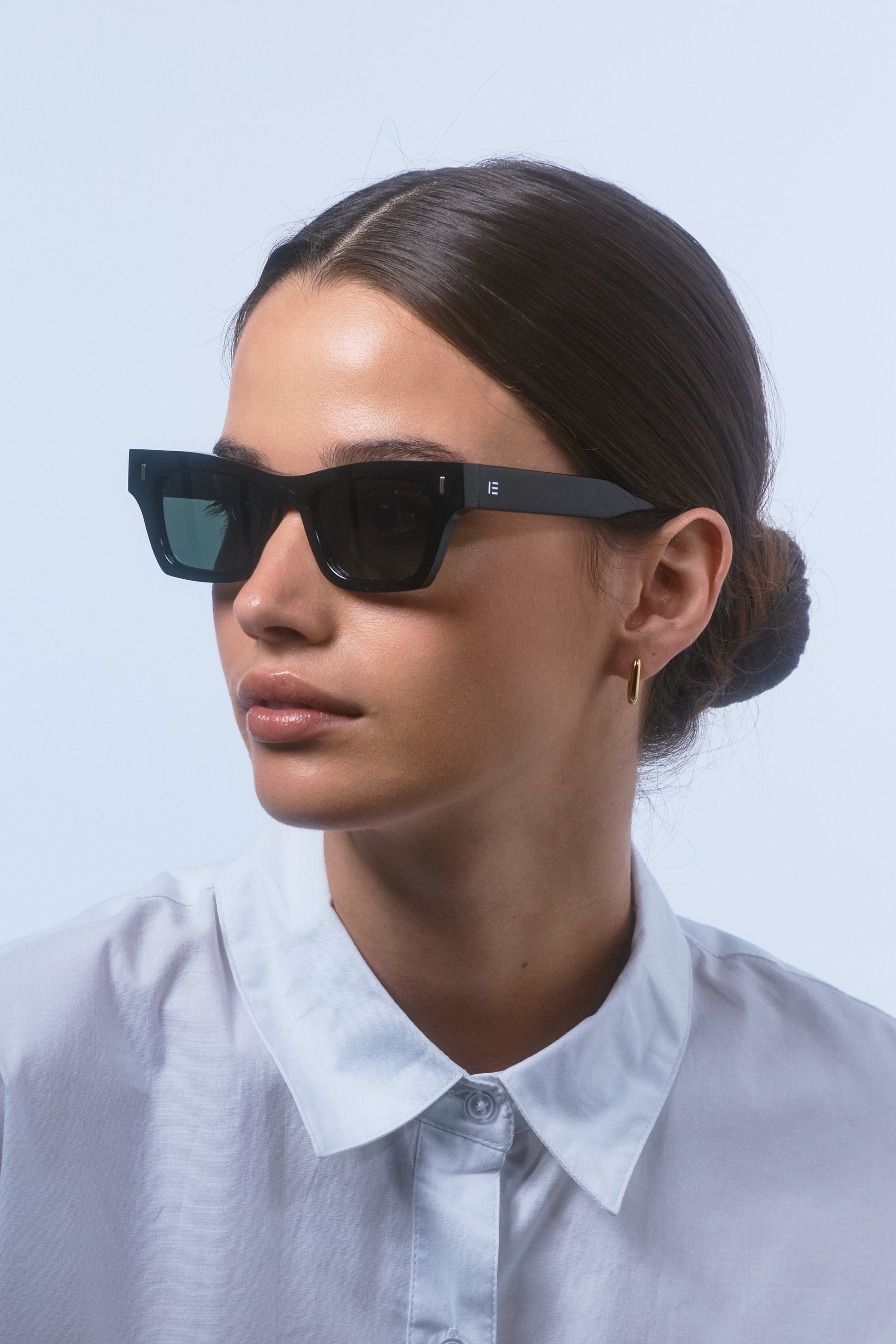 Female model wearing Isle of Eden Olli black sunglasses, angled portrait