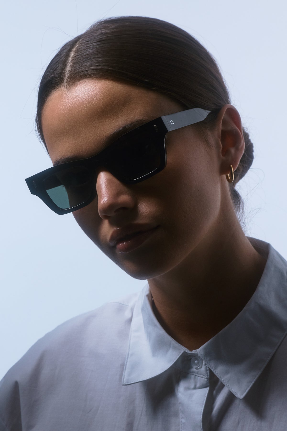 Female model wearing Isle of Eden Olli black sunglasses, angled portrait looking away
