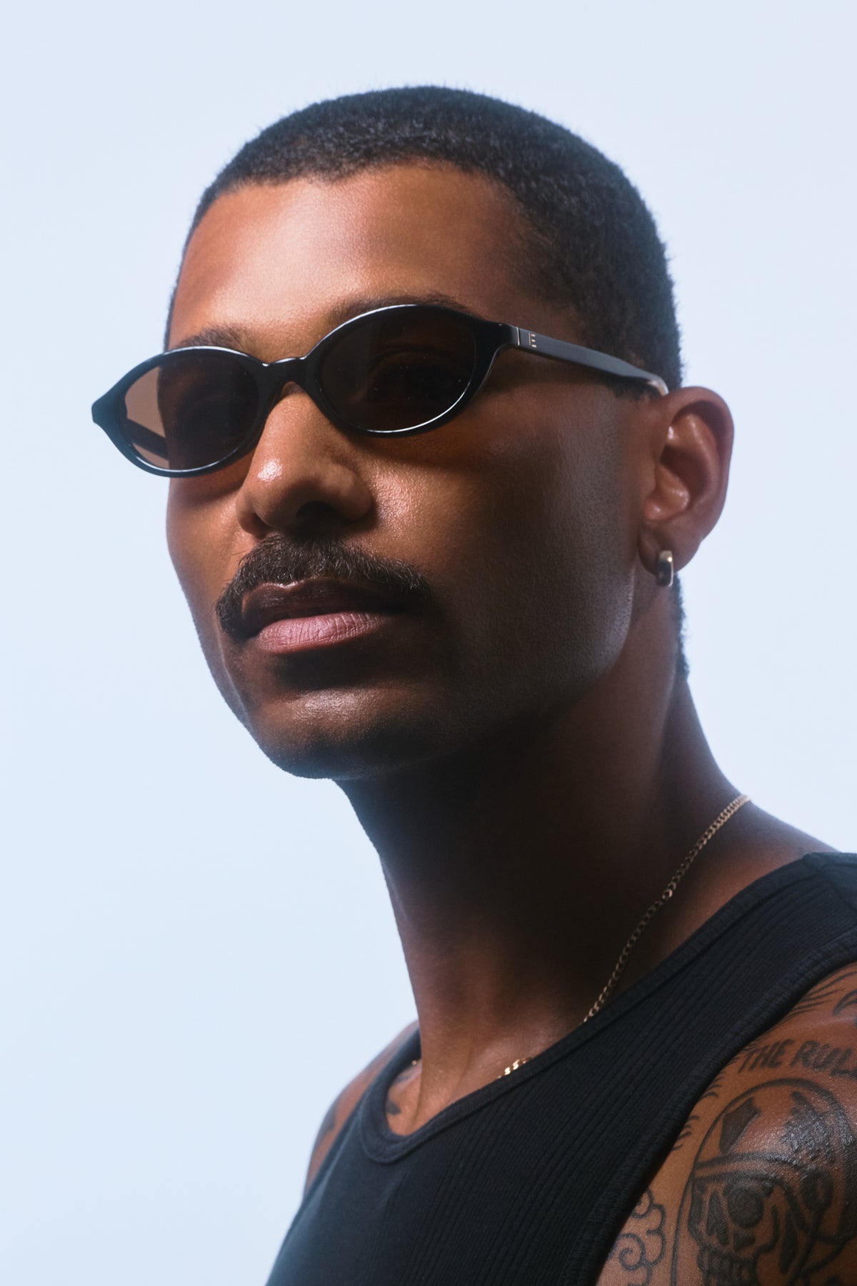 Male model wearing Isle of Eden Mirabel black sunglasses, angled portrait looking away