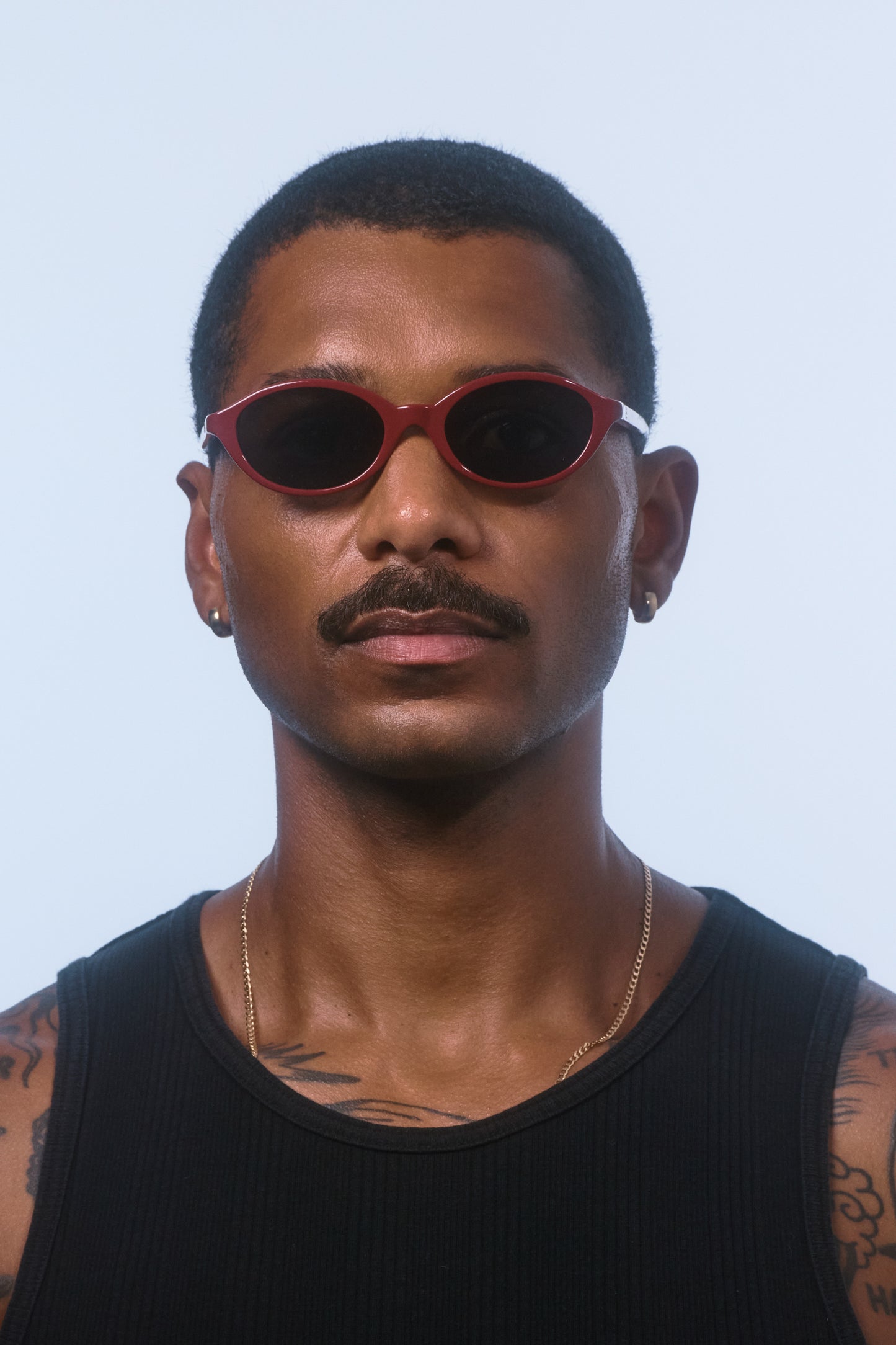 Male model wearing Isle of Eden Mirabel dark red sunglasses, front-facing portrait looking directly at the camera