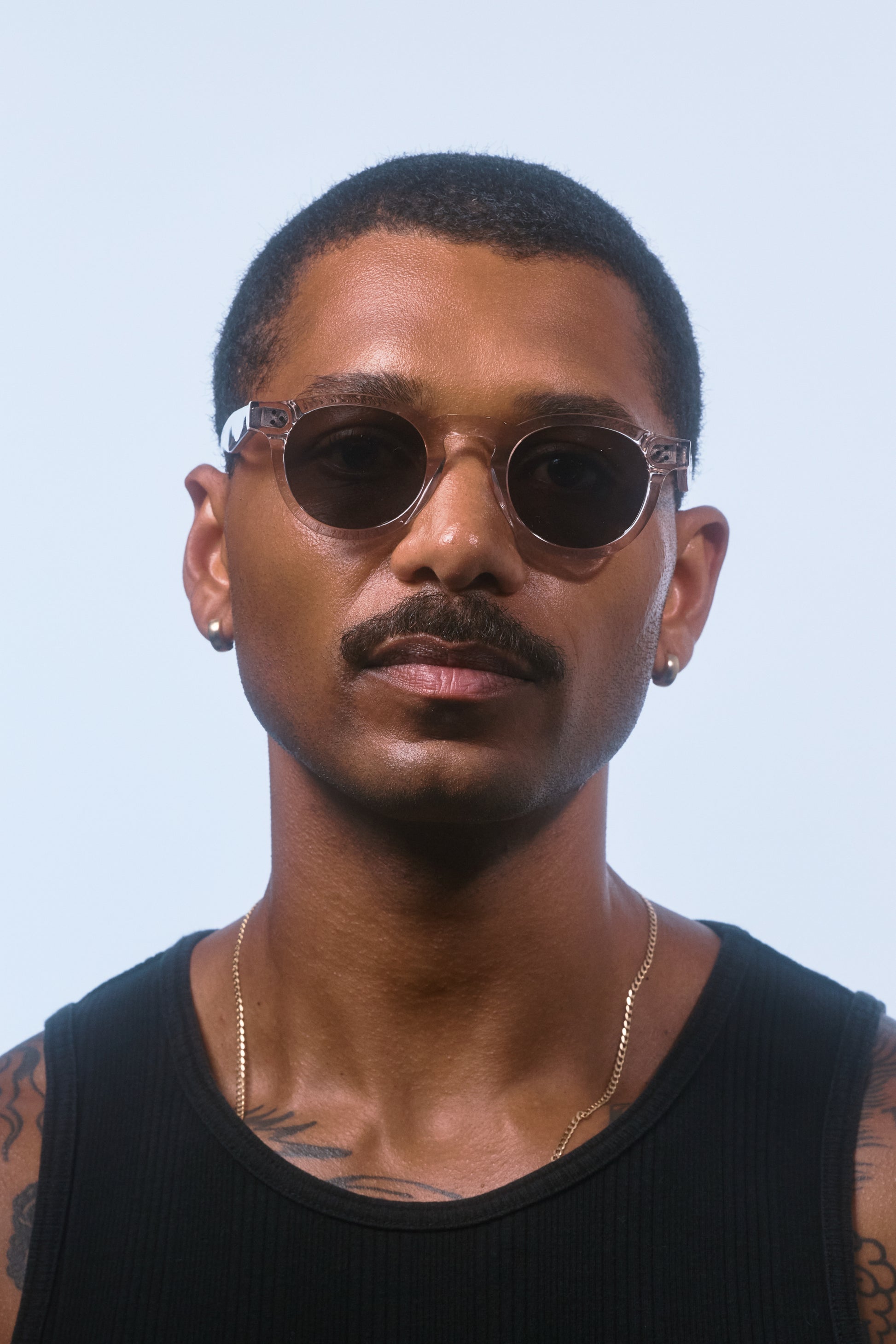 Male model wearing Isle of Eden Drew sand Prescription round sunglasses, looking directly at the camera.