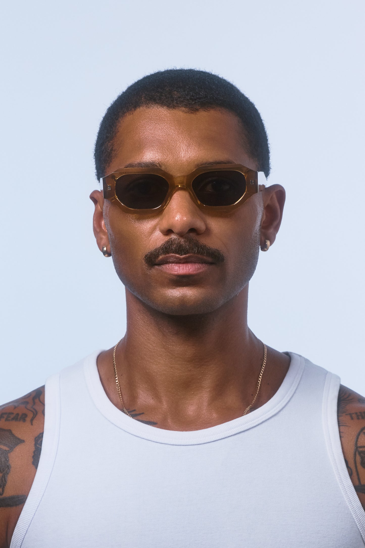Male model wearing Isle of Eden Blake cognac sunglasses, front-facing portrait showing hexagonal frame fit