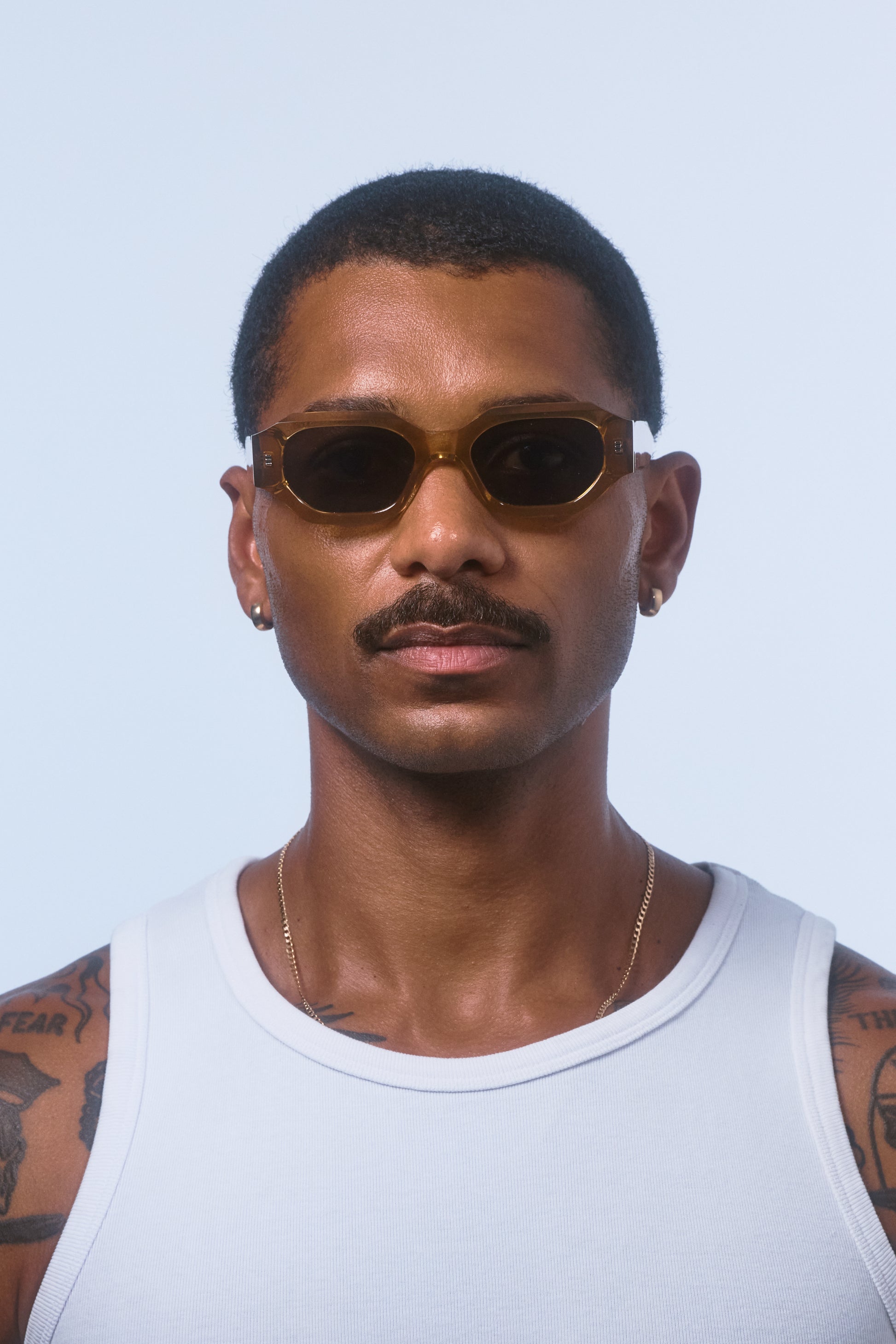 Male model wearing Isle of Eden Blake cognac sunglasses, front-facing portrait showing hexagonal frame fit