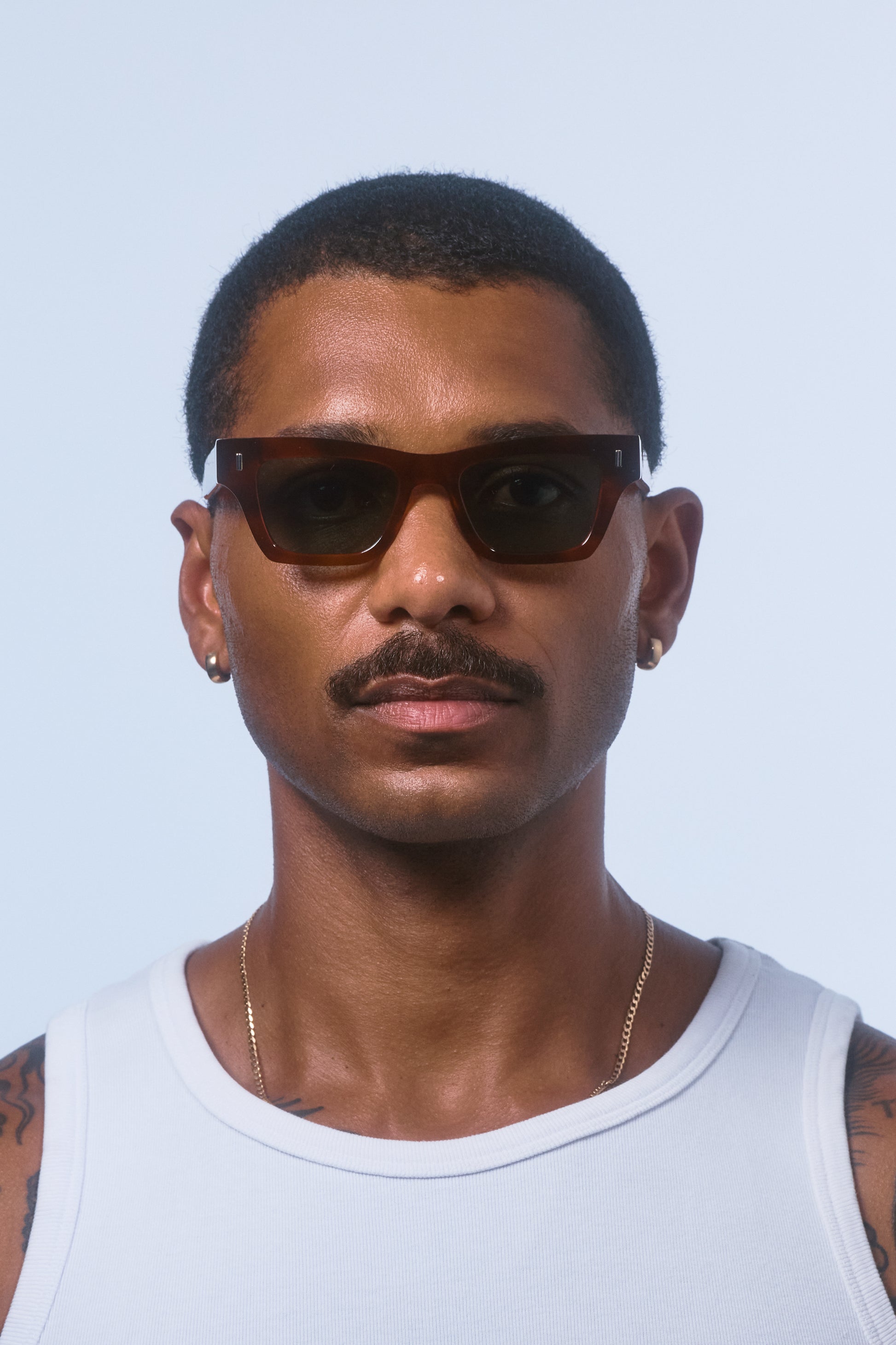 Male model wearing Isle of Eden Olli honey tortoise sunglasses, front-facing portrait looking directly at the camera