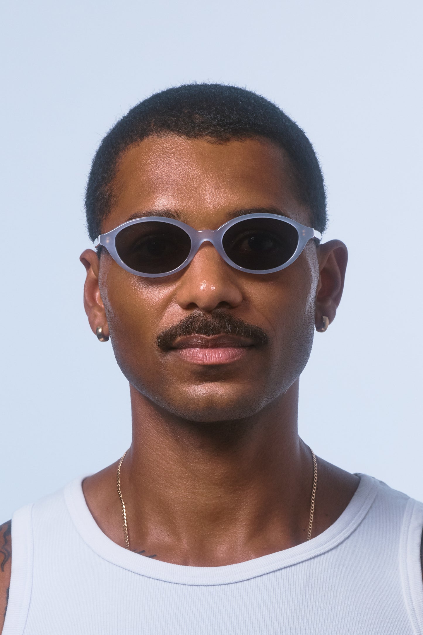 Male model wearing Isle of Eden Mirabel baby blue sunglasses, front-facing portrait