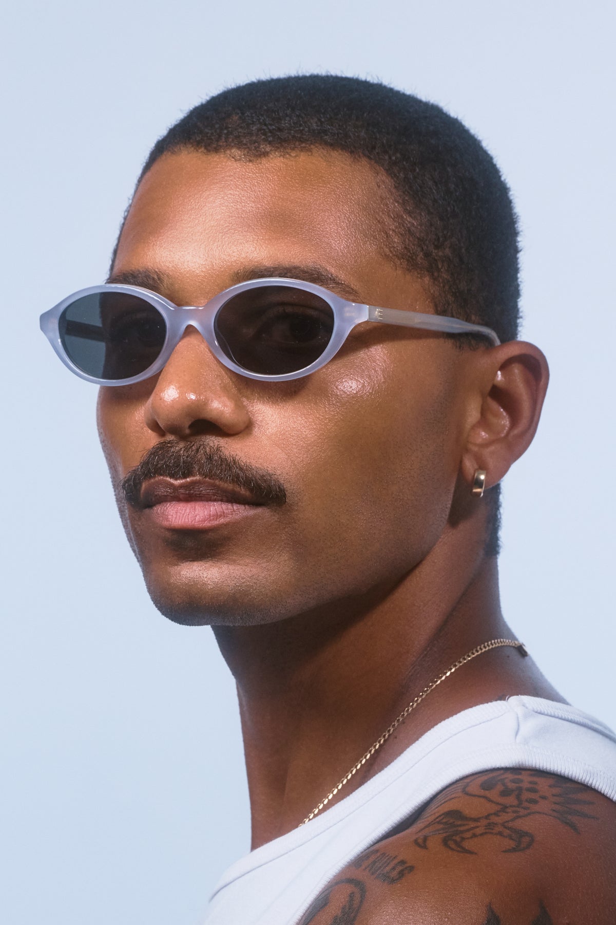 Male model wearing Isle of Eden Mirabel baby blue sunglasses, angled portrait looking away
