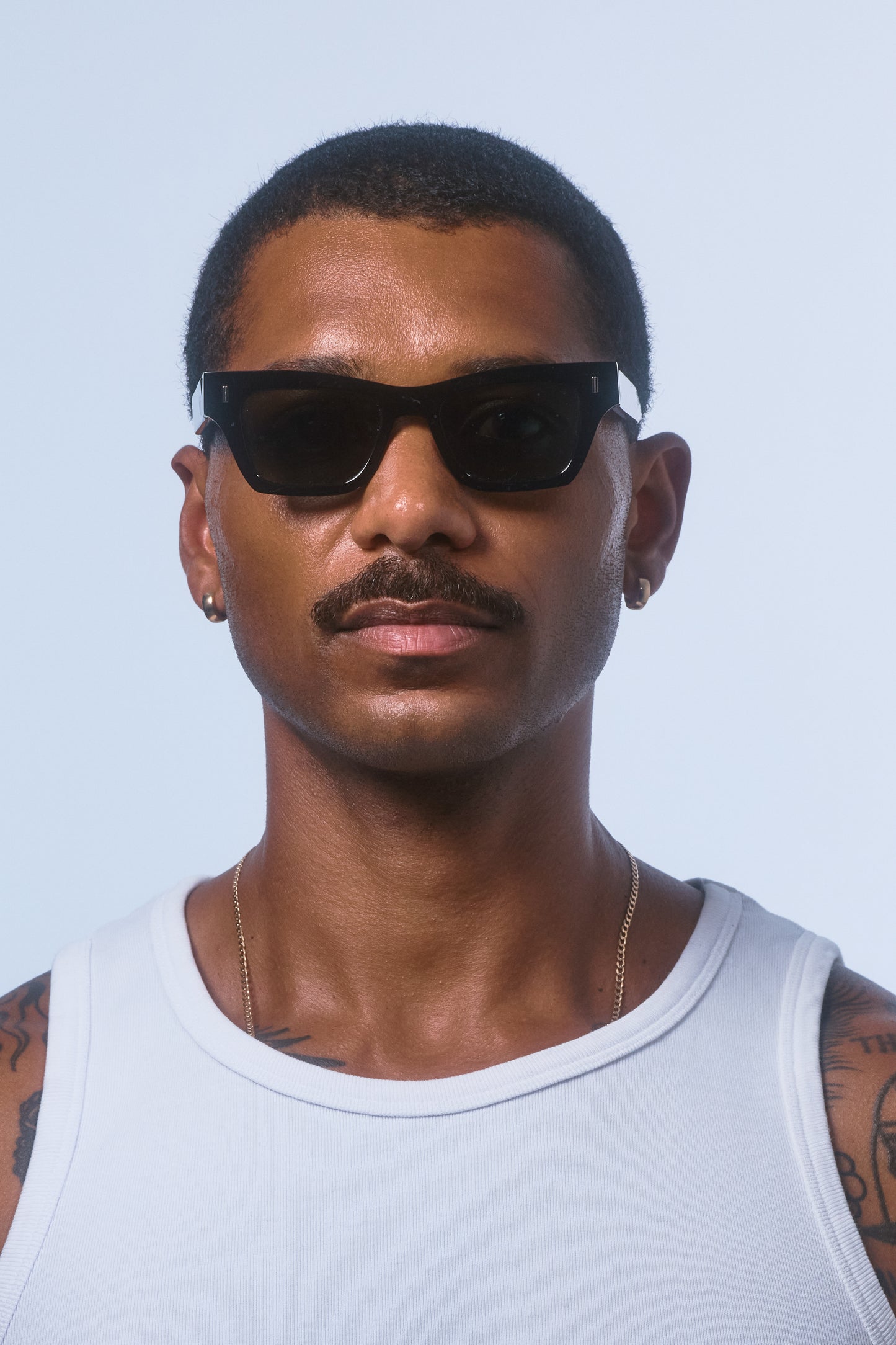 Male model wearing Isle of Eden Olli black sunglasses, front-facing portrait looking directly at the camera