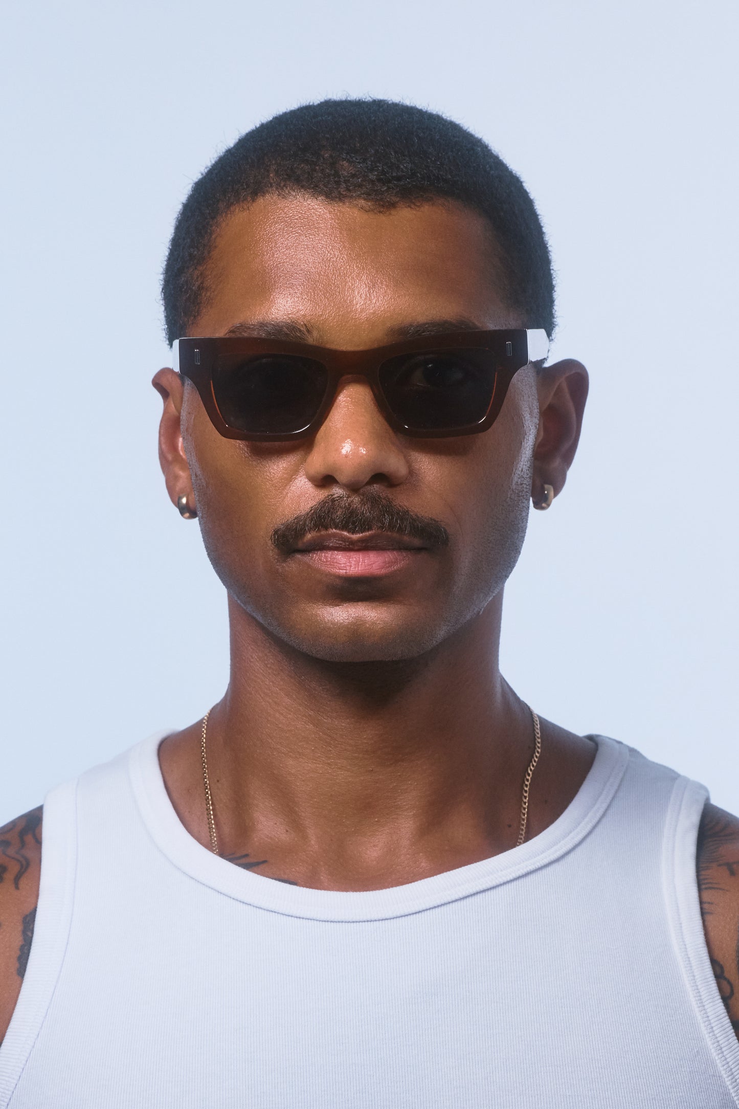 Male model wearing Isle of Eden Olli brown sunglasses, front-facing portrait looking directly at the camera