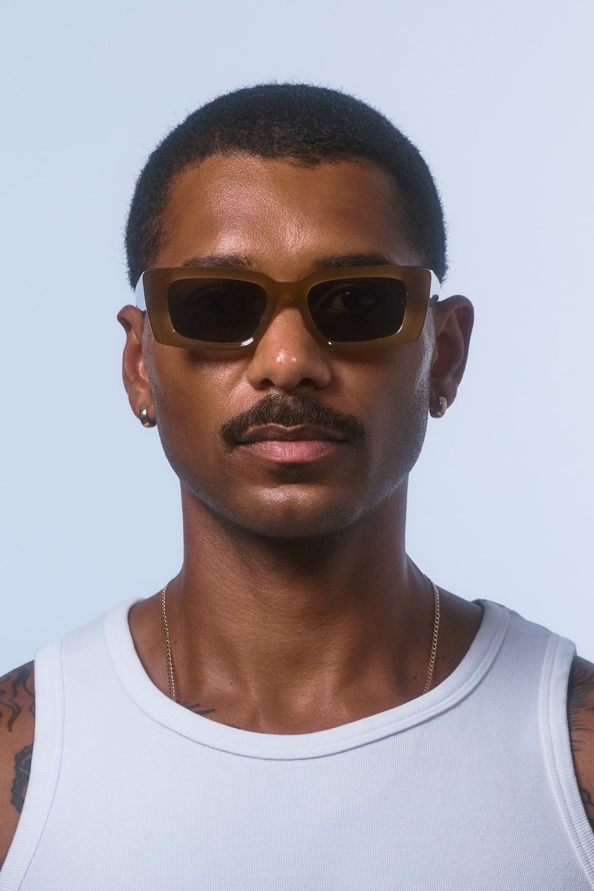 Male model wearing Isle of Eden Goldie dijon sunglasses, front-facing portrait looking directly at the camera