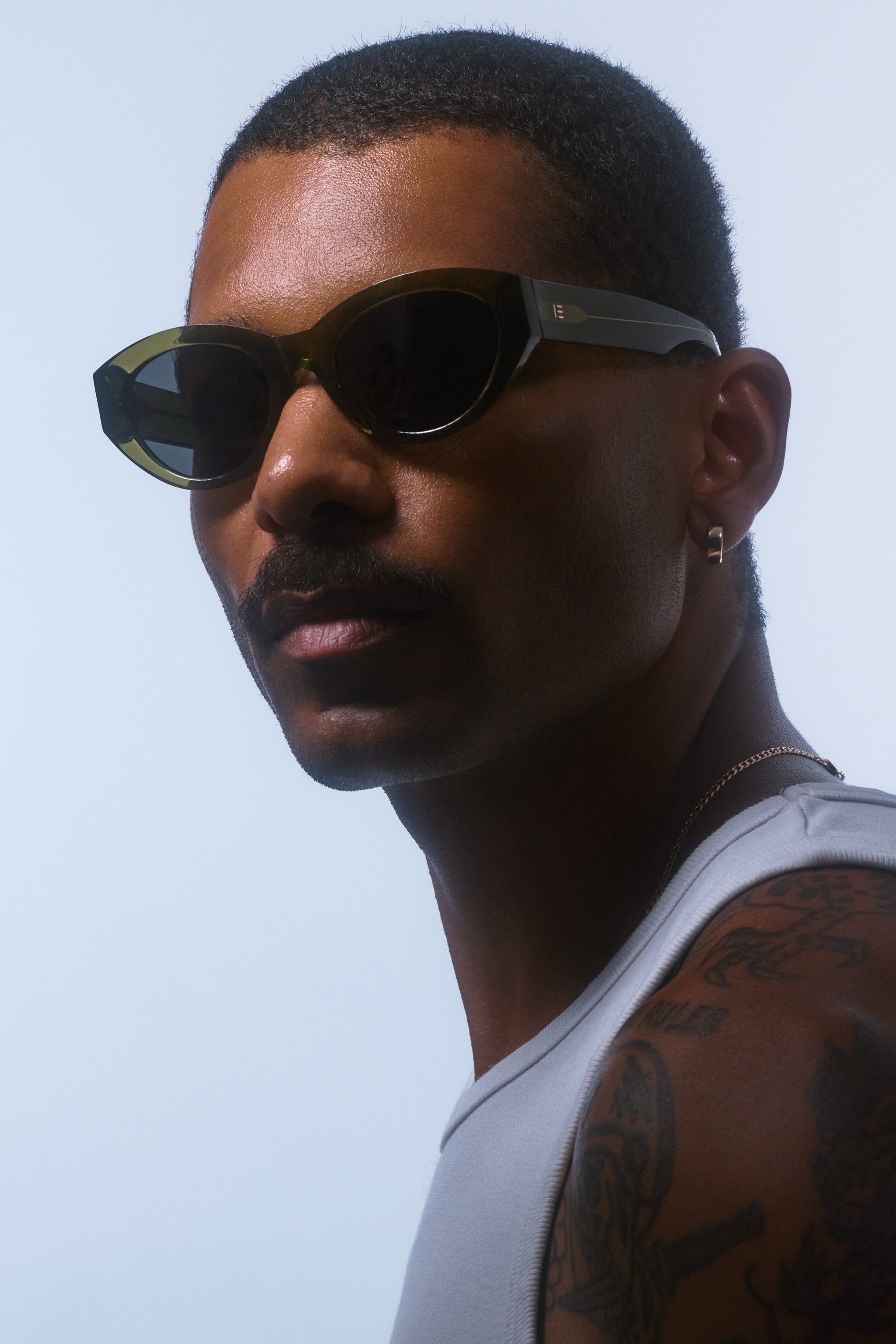 Male model wearing Isle of Eden Felina frosted green sunglasses, angled portrait