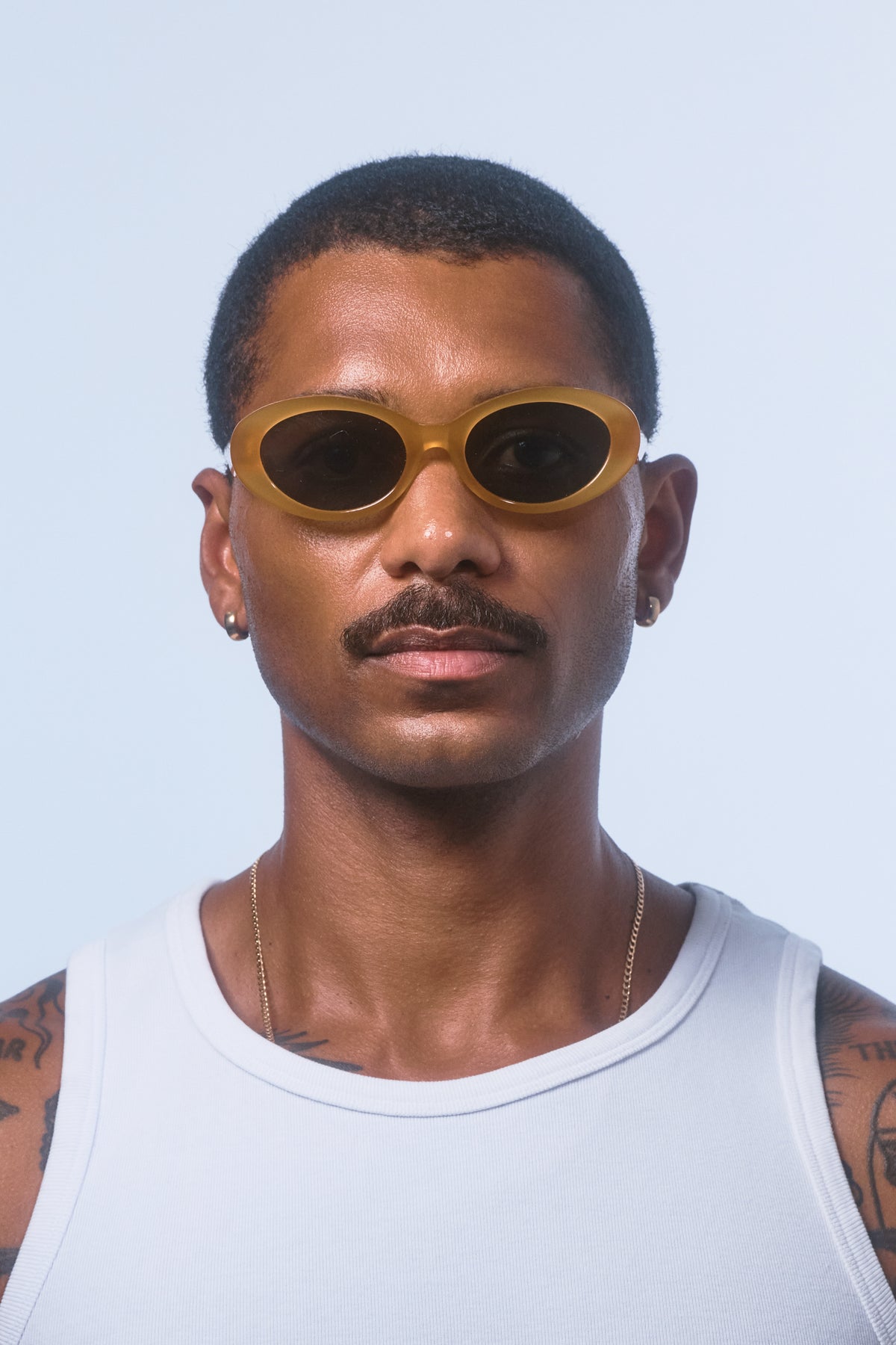 Male model wearing Isle of Eden Frankie yellow sunglasses, front-facing portrait looking directly at the camera