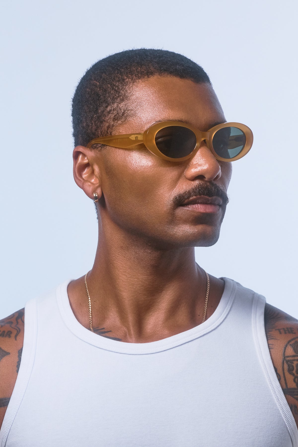 Male model wearing Isle of Eden Frankie yellow sunglasses, angled portrait looking away