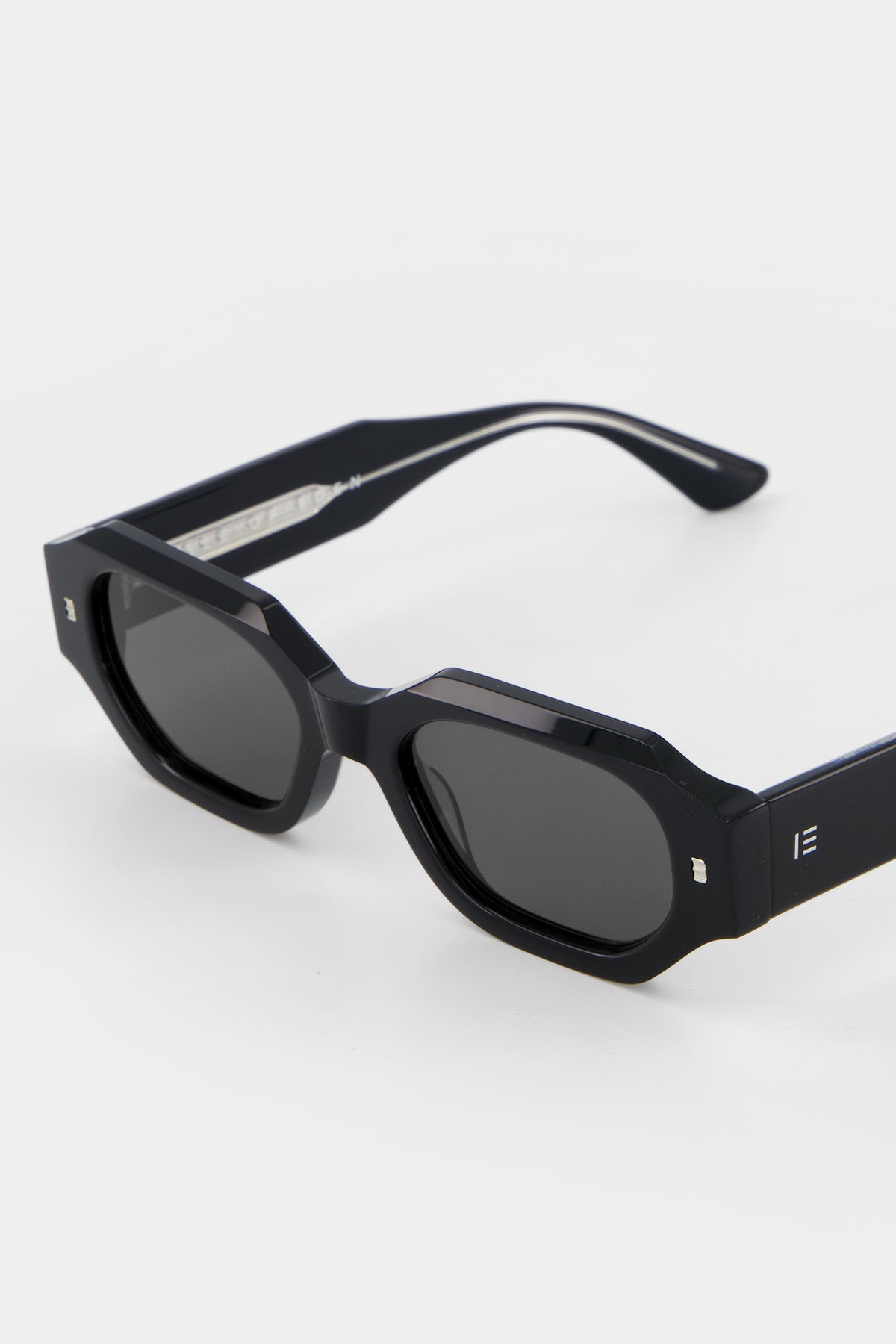 Close-up of Isle of Eden Blake black sunglasses showing filigree wire temple core and IE monogram detail