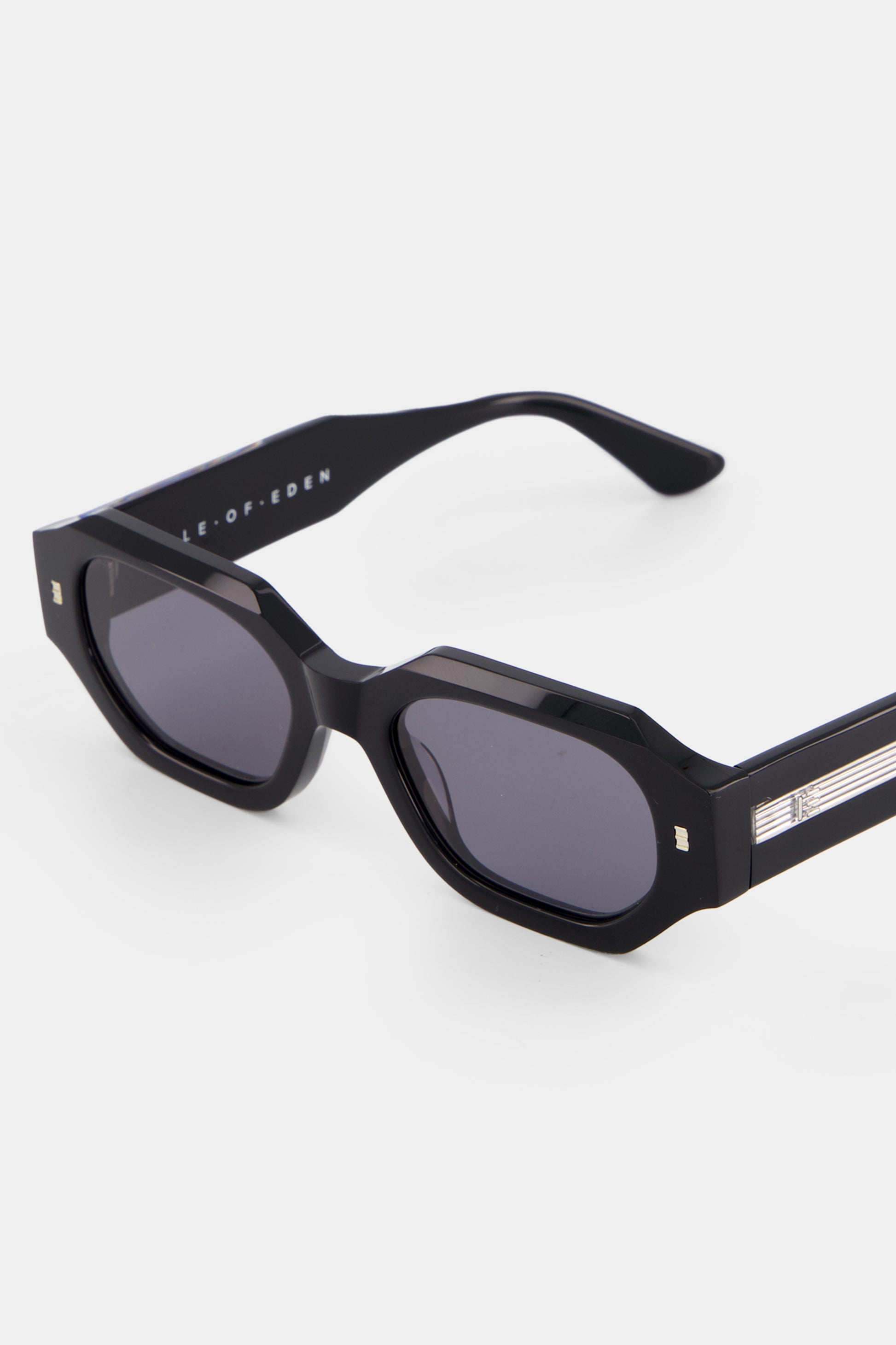 Close-up of Isle of Eden Blake Black Wire sunglasses showing exposed wire temple core and brand lettering