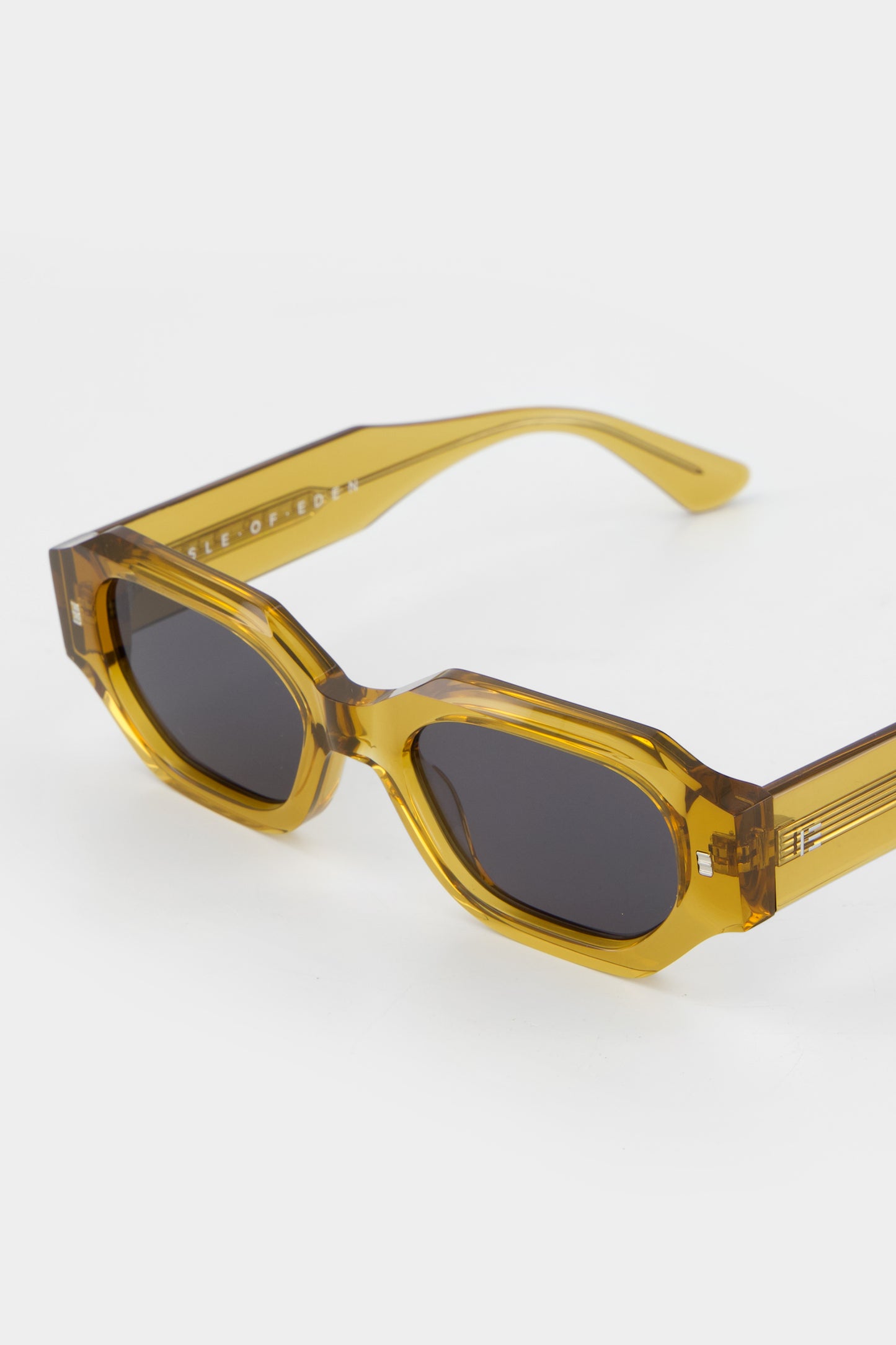 Isle of Eden Blake cognac sunglasses, angled three-quarter view showing hexagonal frame and brand lettering on the temple arm
