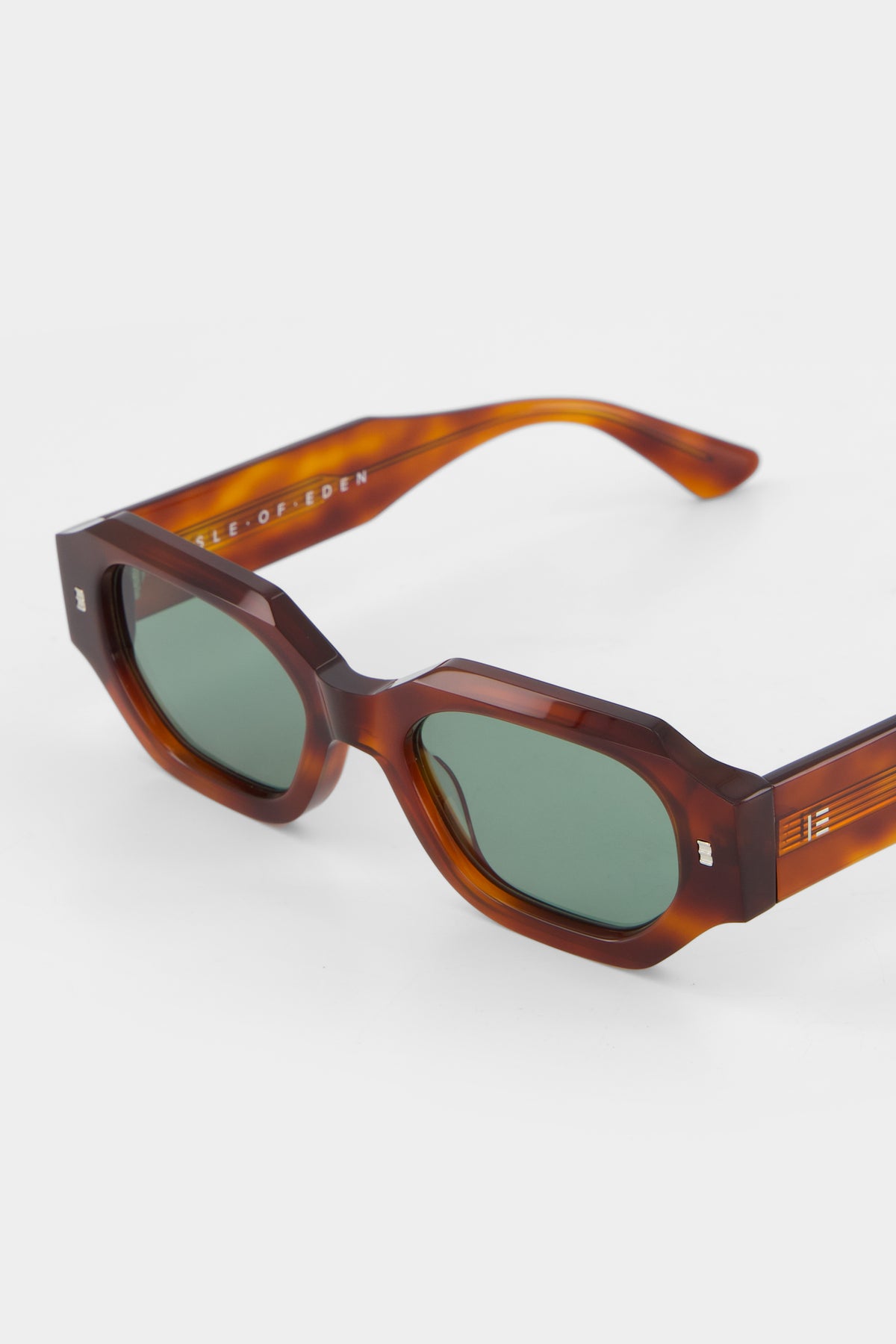 Close-up of Isle of Eden Blake honey tortoise sunglasses showing filigree wire temple core and brand lettering