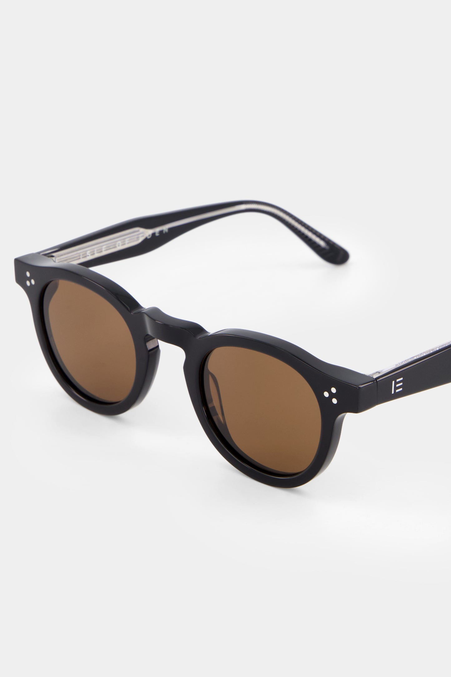 Close-up of Isle of Eden Drew black sunglasses showing round frame and brand lettering
