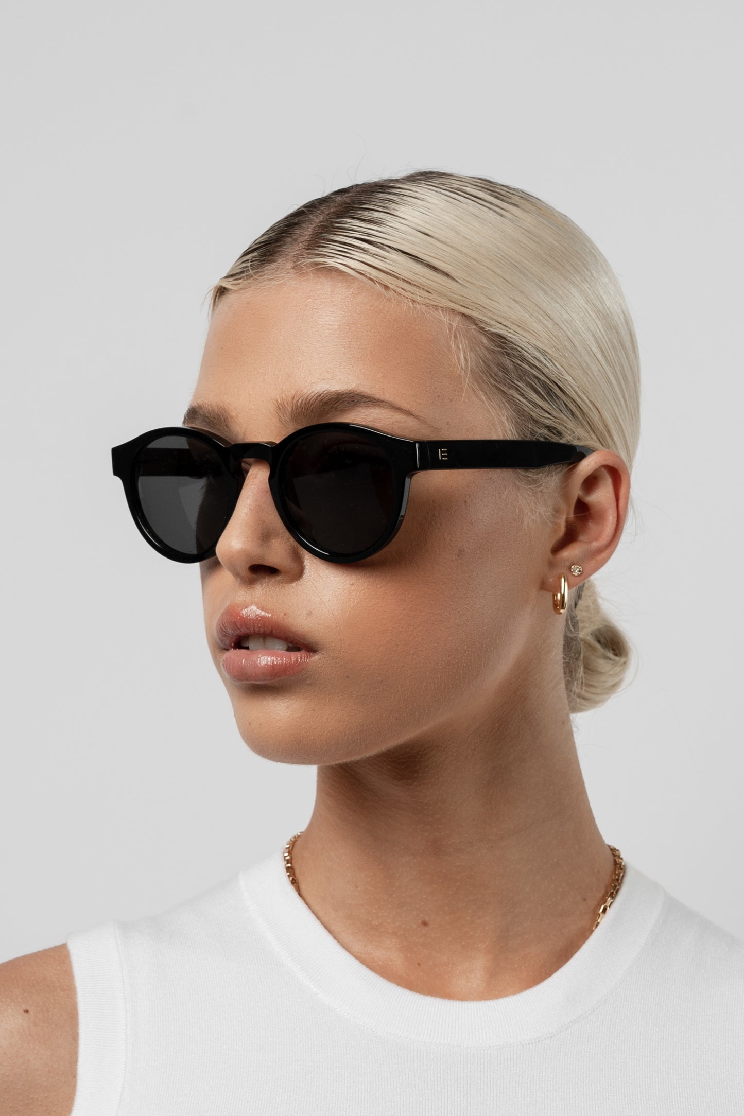 Female model wearing Isle of Eden Eddie black sunglasses, angled portrait looking up