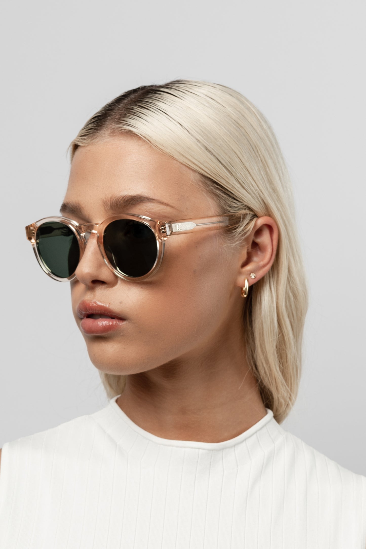 Female model wearing Isle of Eden Eddie champagne sunglasses, angled side profile portrait