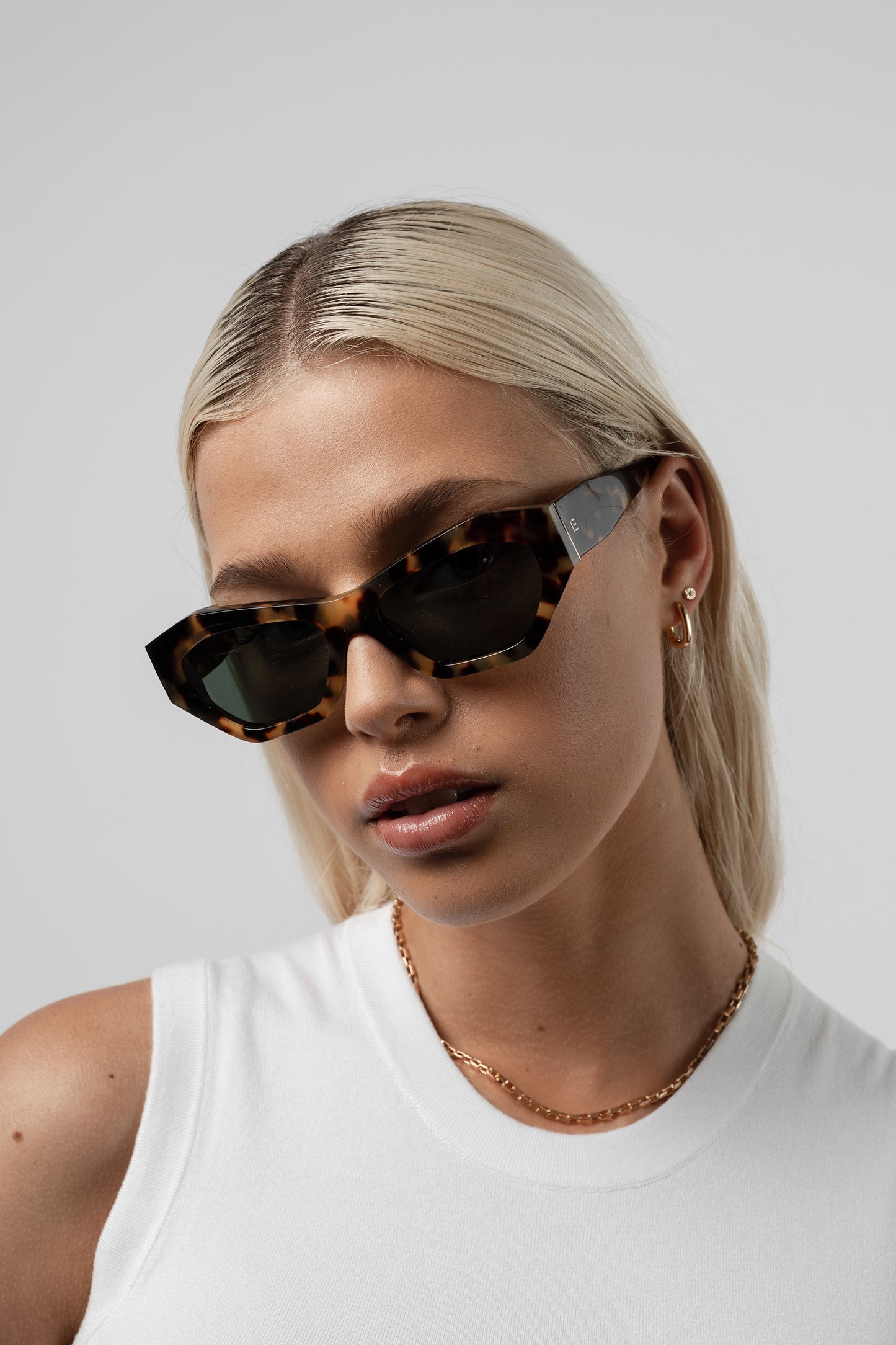 Female model wearing Isle of Eden Emily tortoise sunglasses, angled portrait looking down