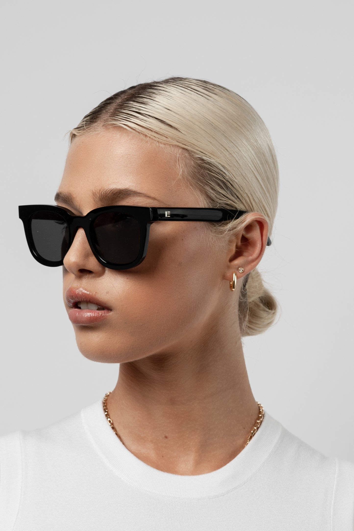 Female model wearing Isle of Eden Eugene black sunglasses, angled portrait