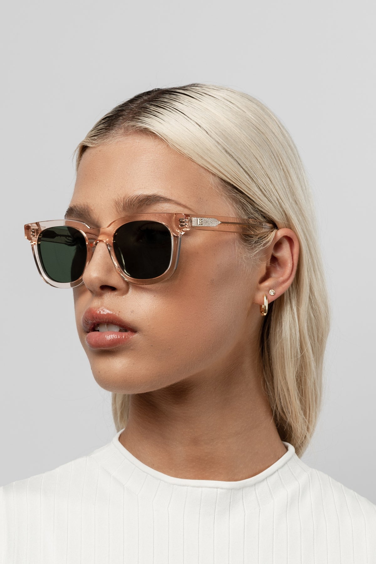 Female model wearing Isle of Eden Eugene champagne sunglasses, angled portrait