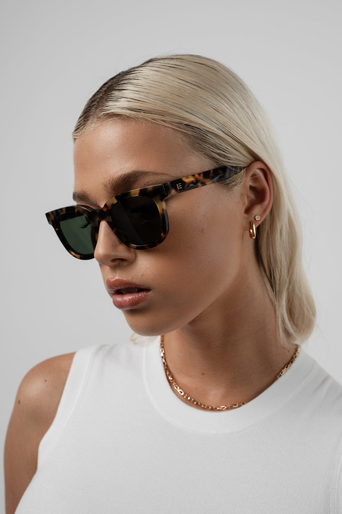 Female model wearing Isle of Eden Eugene tortoise sunglasses, angled portrait looking away