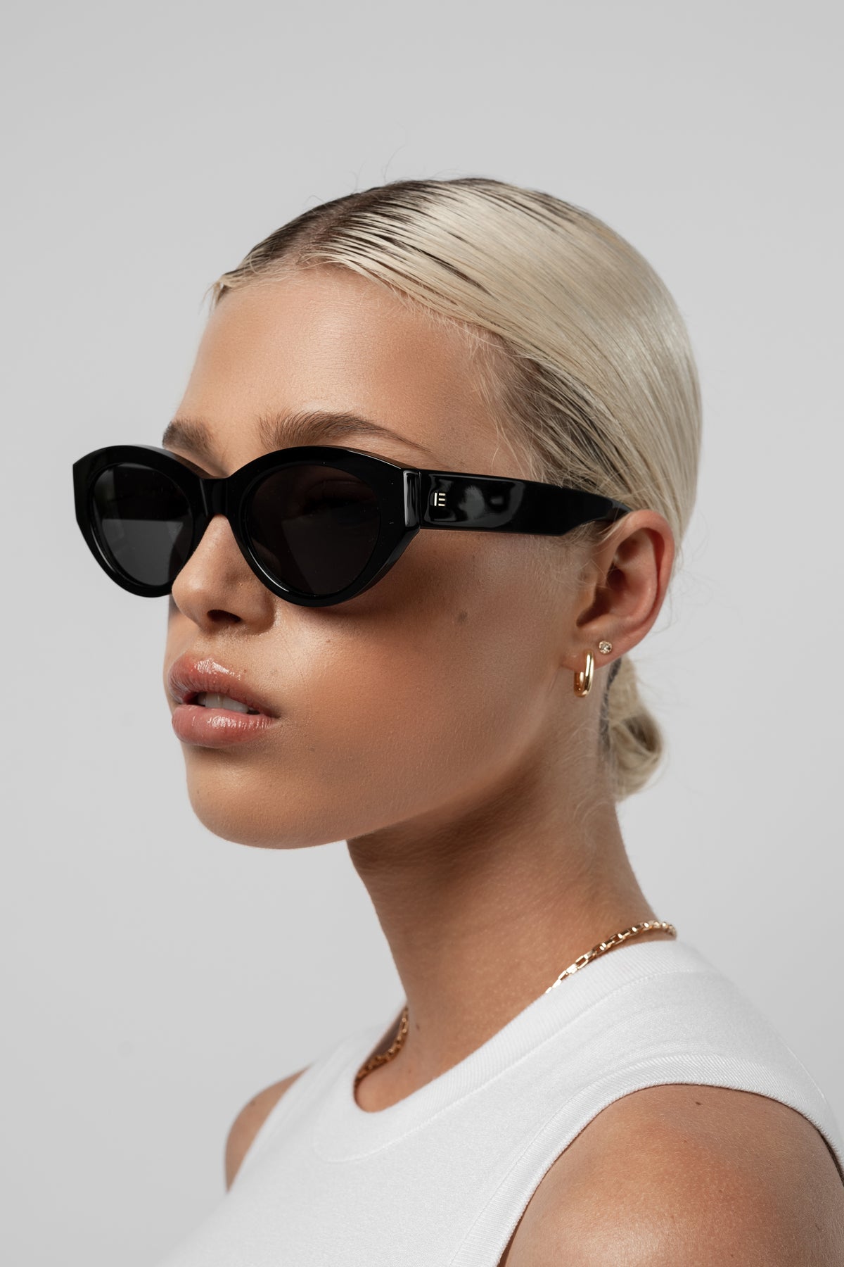 Female model wearing Isle of Eden Felina black sunglasses, angled portrait looking away