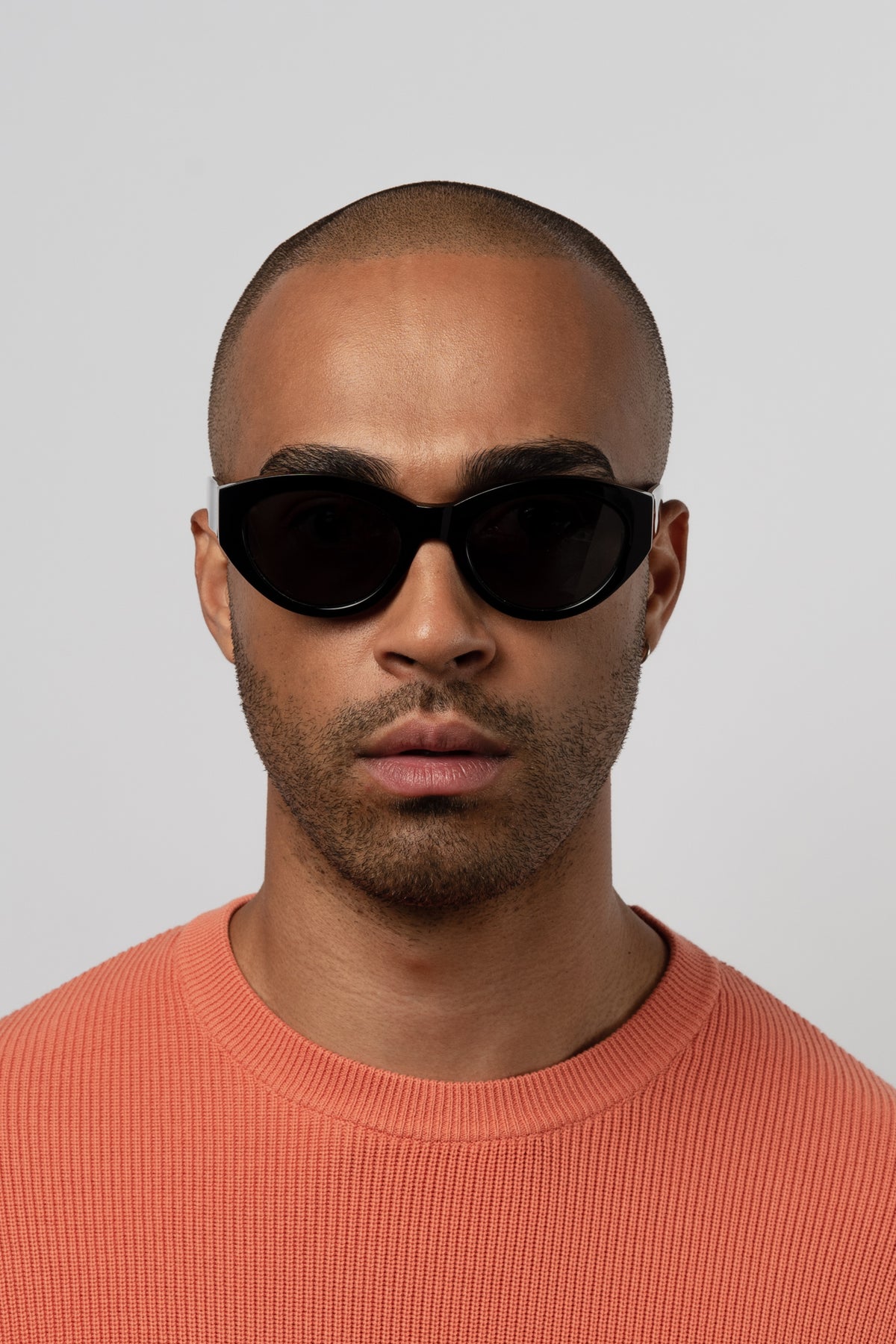 Male model wearing Isle of Eden Felina black sunglasses, front-facing portrait looking directly at the camera