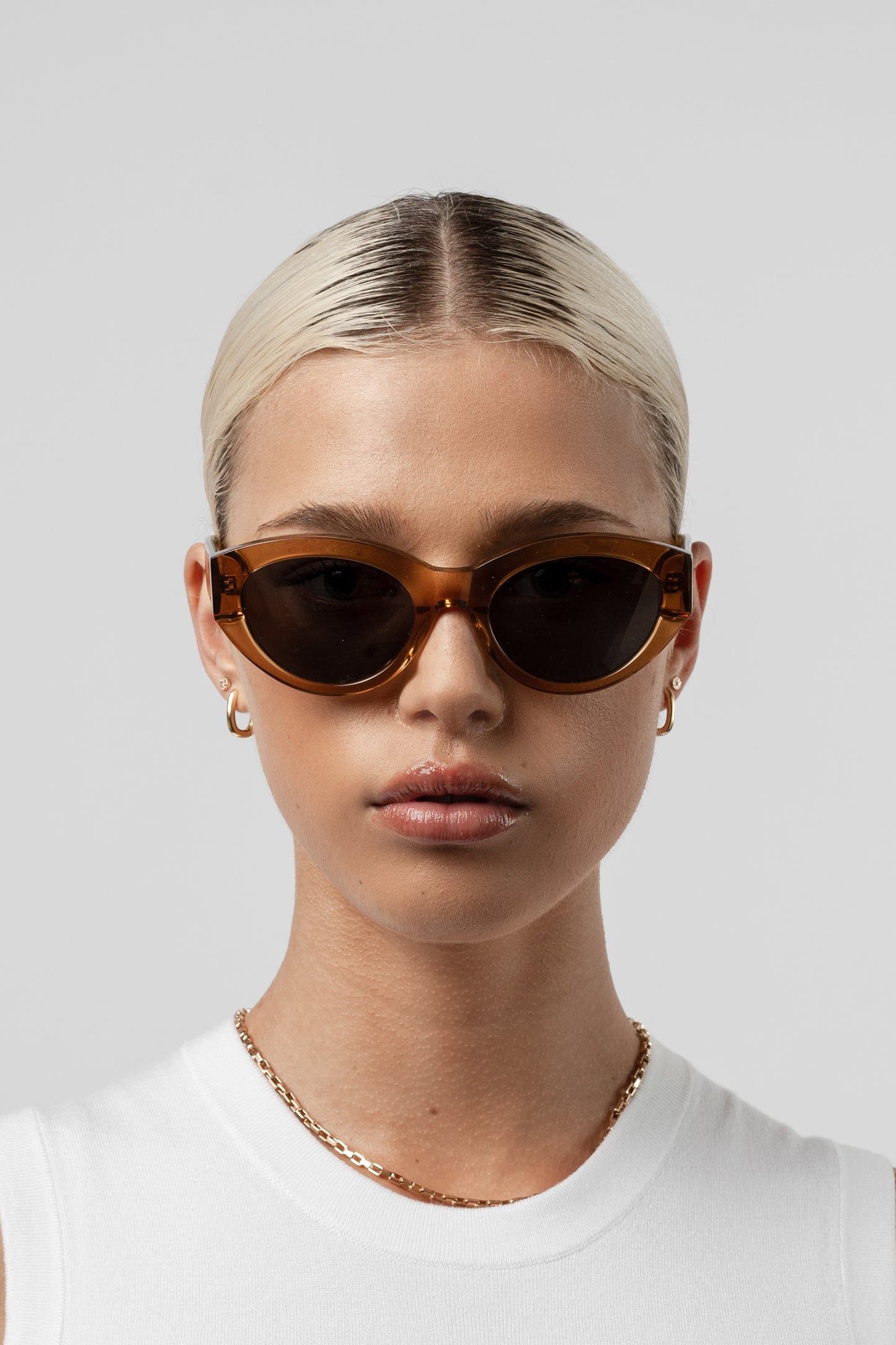 Female model wearing Isle of Eden Felina cognac sunglasses, front-facing portrait looking directly at the camera