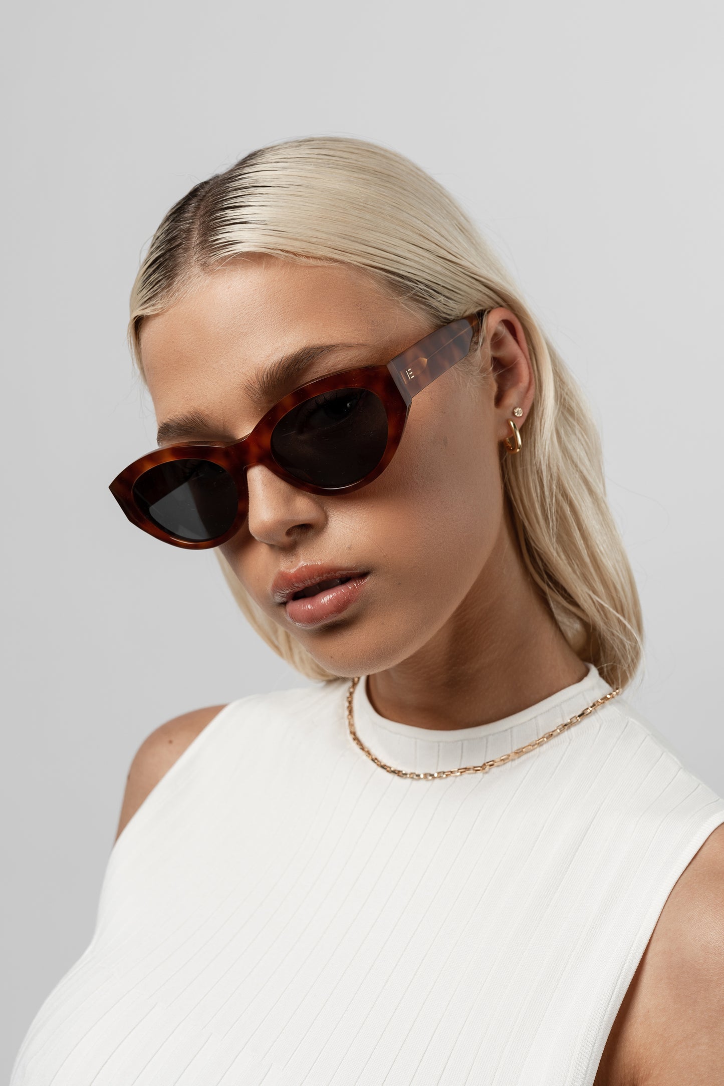 Female model wearing Isle of Eden Felina whisky tortoise sunglasses, angled portrait looking away