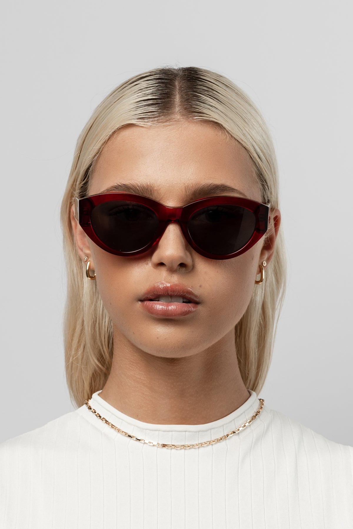 Female model wearing Isle of Eden Felina red sunglasses, front-facing portrait looking directly at the camera