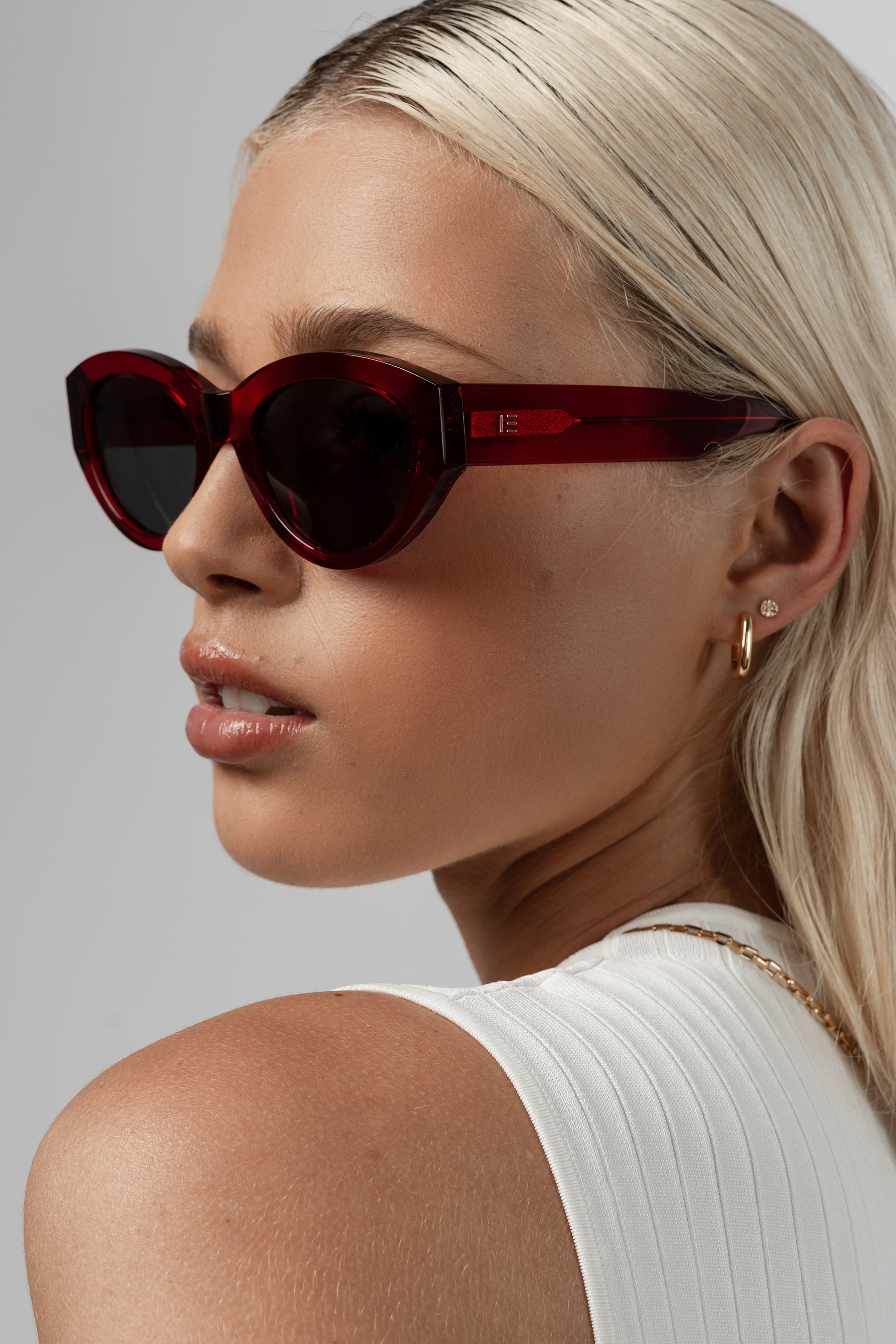 Female model wearing Isle of Eden Felina red sunglasses, side profile portrait looking away
