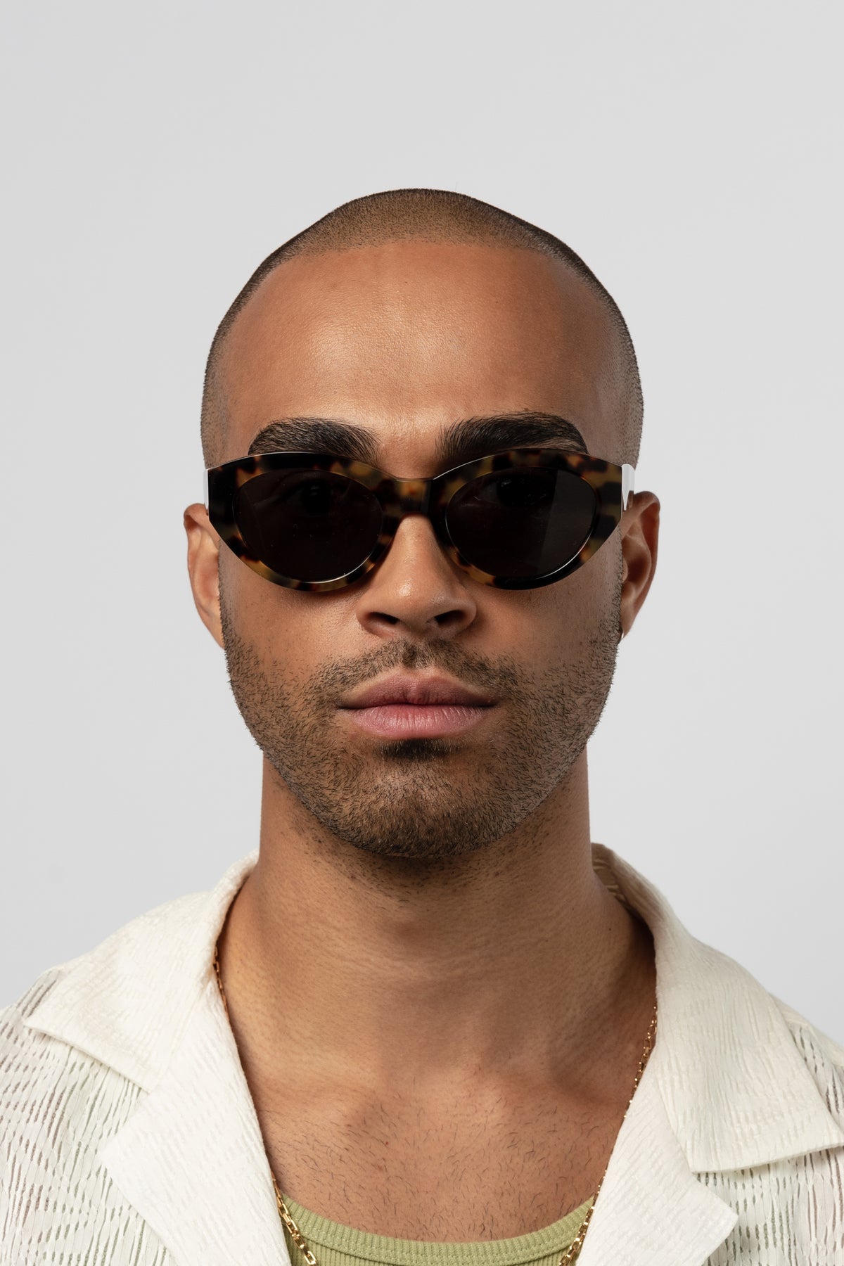 Male model wearing Isle of Eden Felina tortoise sunglasses, front-facing portrait looking directly at the camera