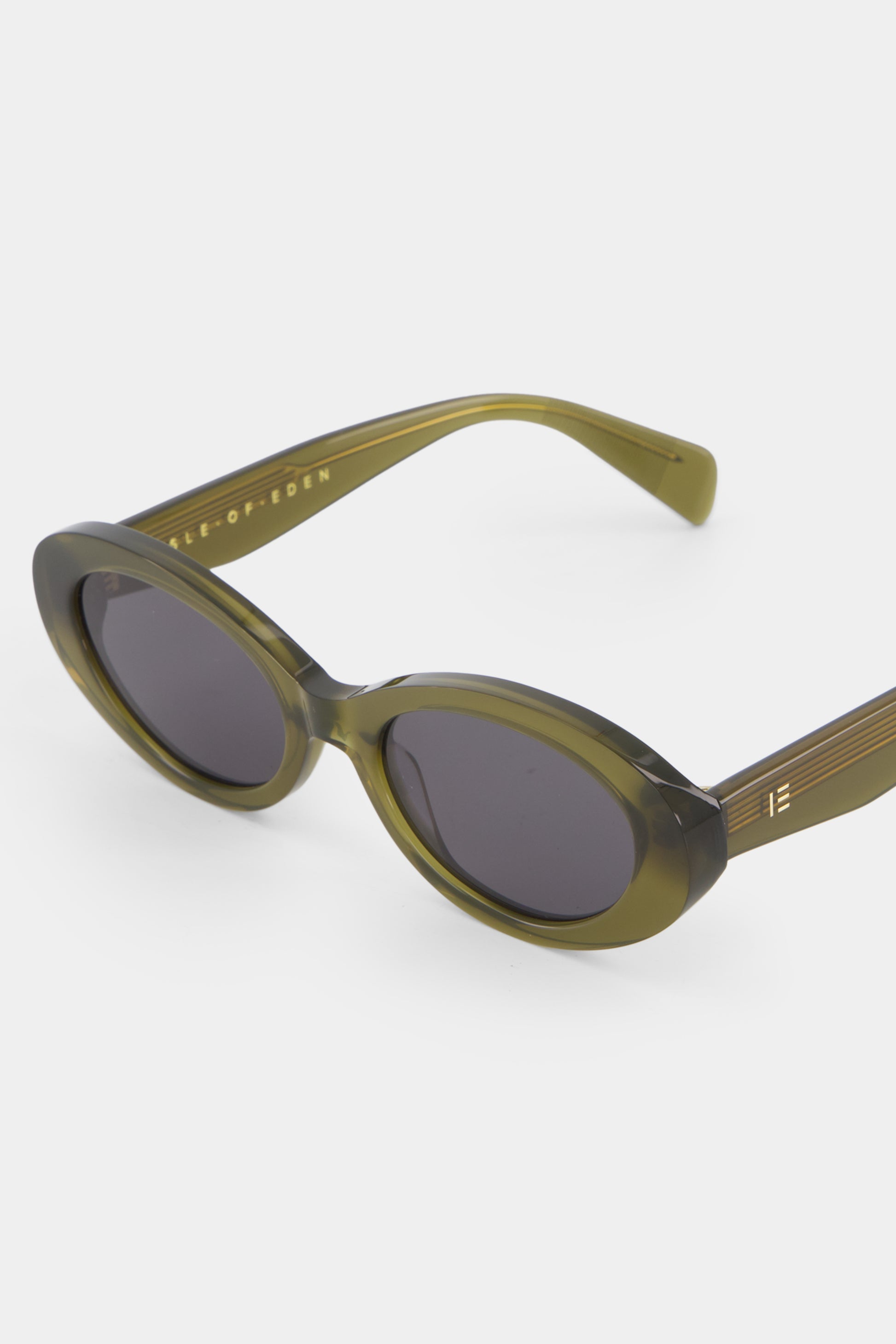 Close-up of Isle of Eden Frankie frosted green sunglasses showing curvy oval frame and brand lettering